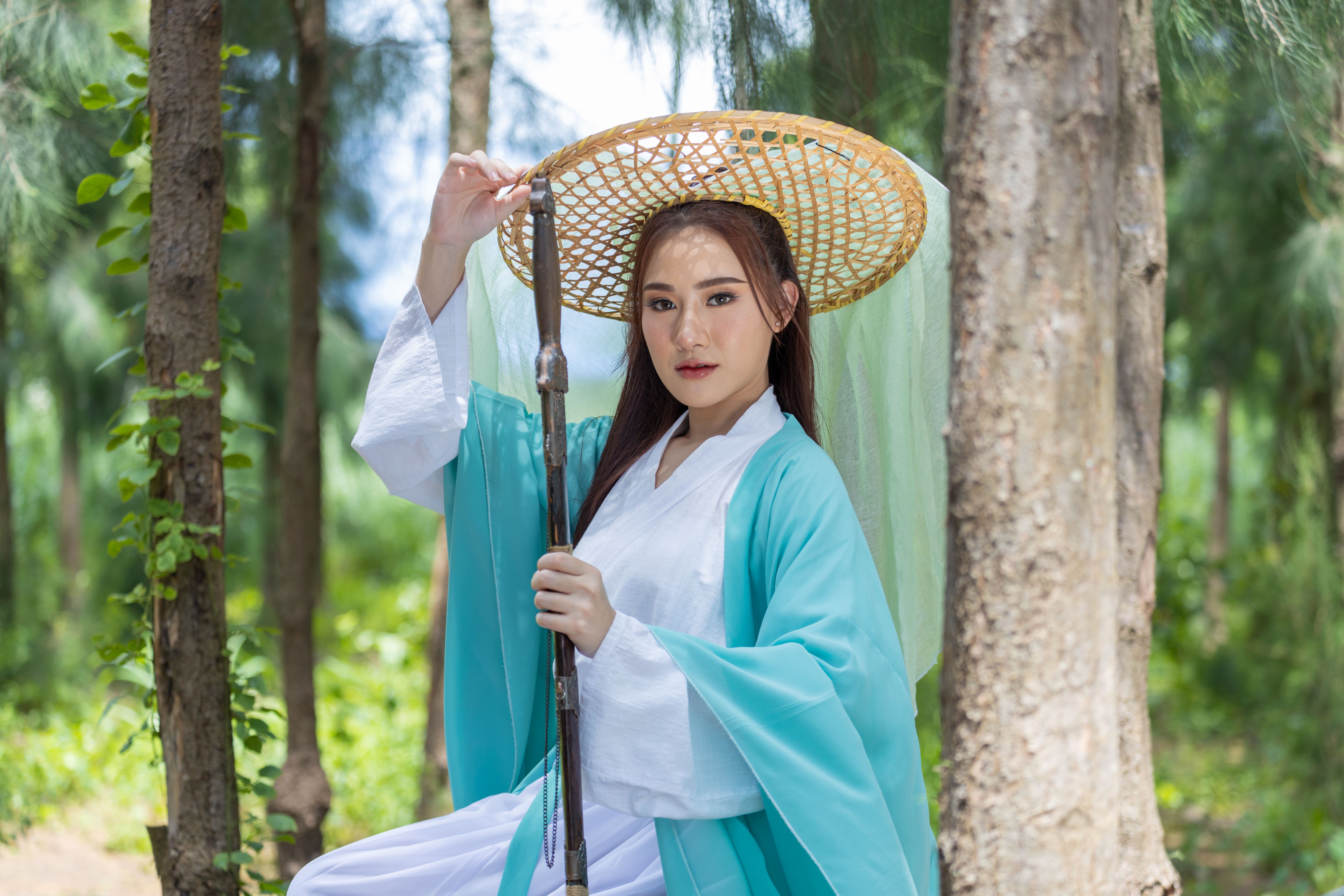 Young beautiful Asian woman dressed in ancient Chinese warrior style with ancient fan. cute girl in green dress