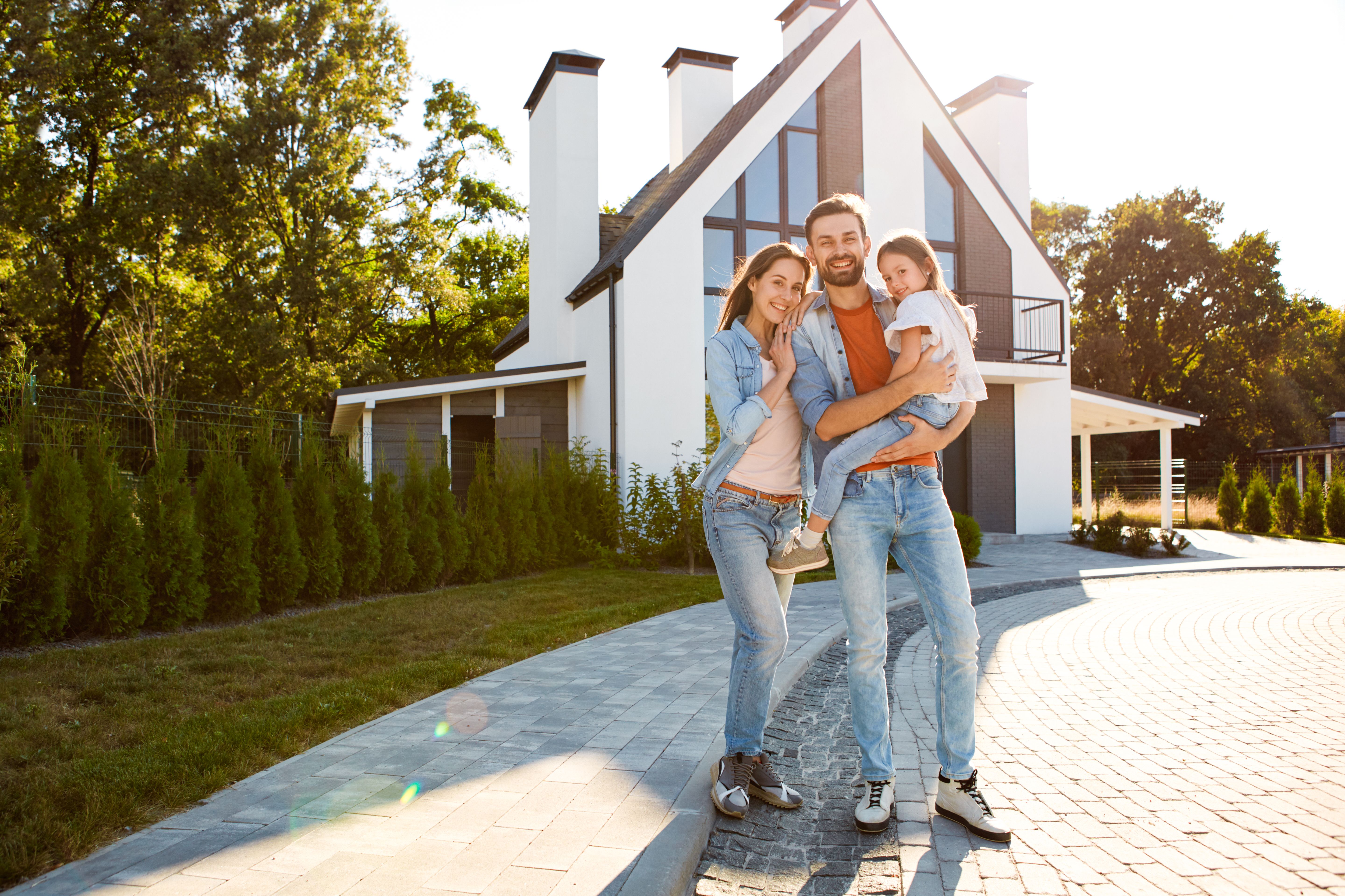 Family standing together against new house and smiling wide
