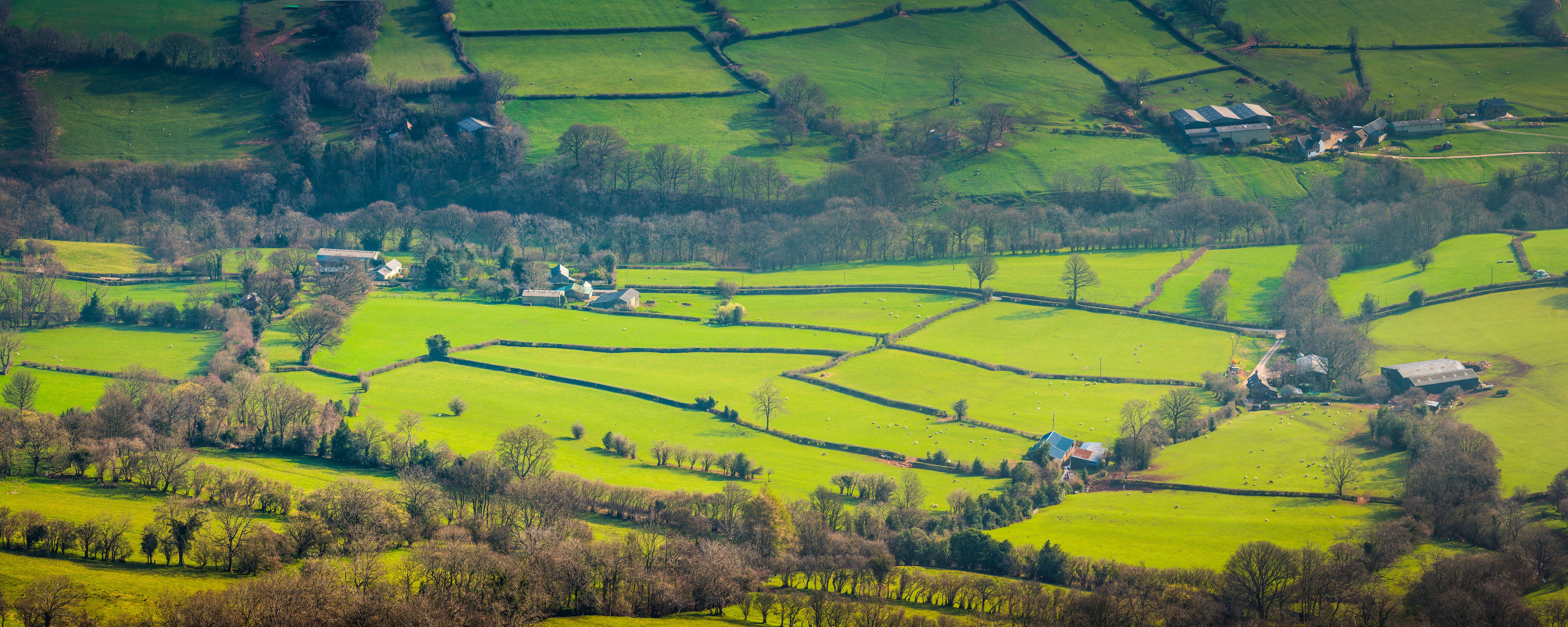 Green fields patchwork pasture mountain valley hill farms agriculture panorama