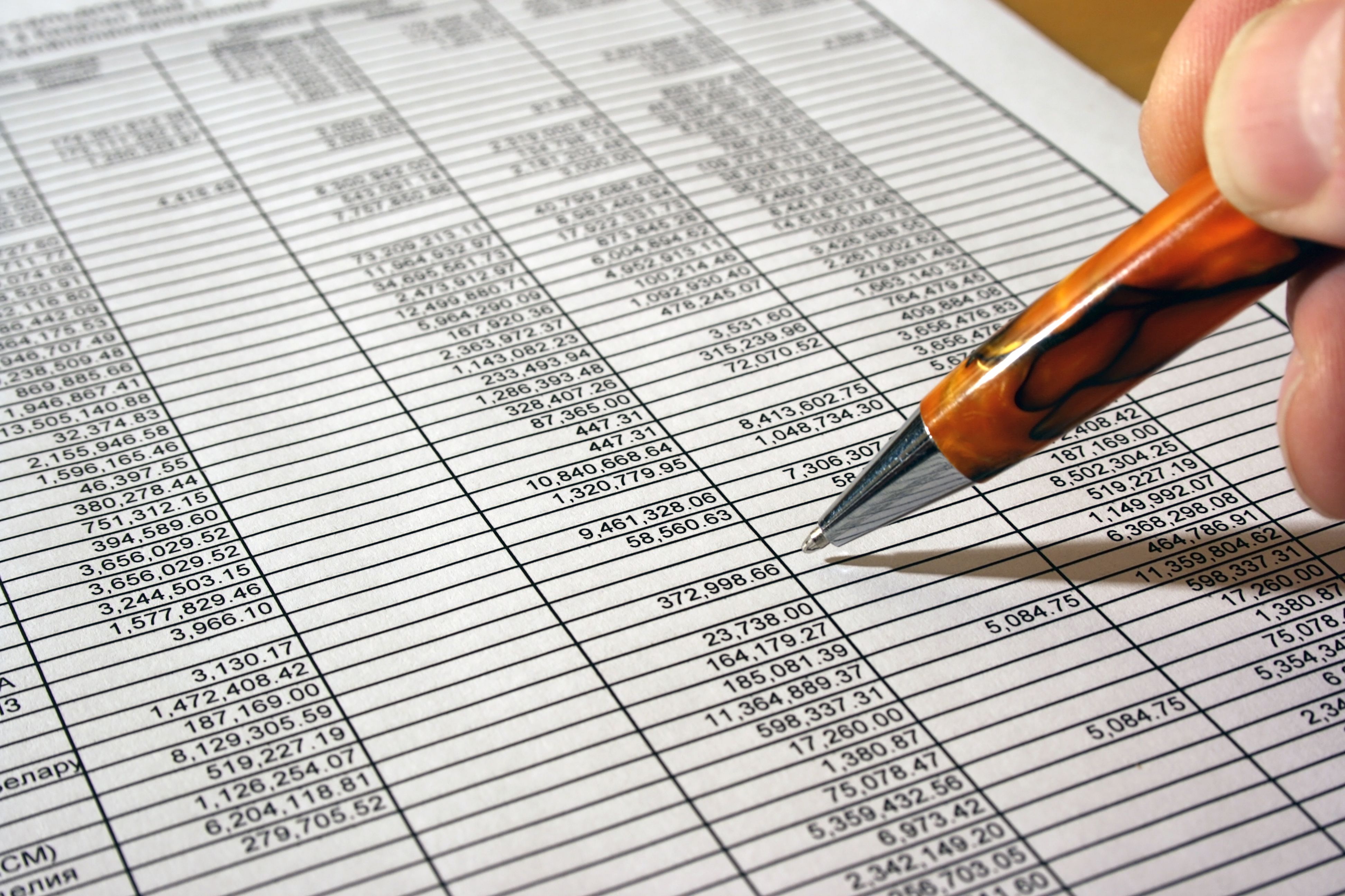 Ballpoint pen going over a sheet of numbers for calculation