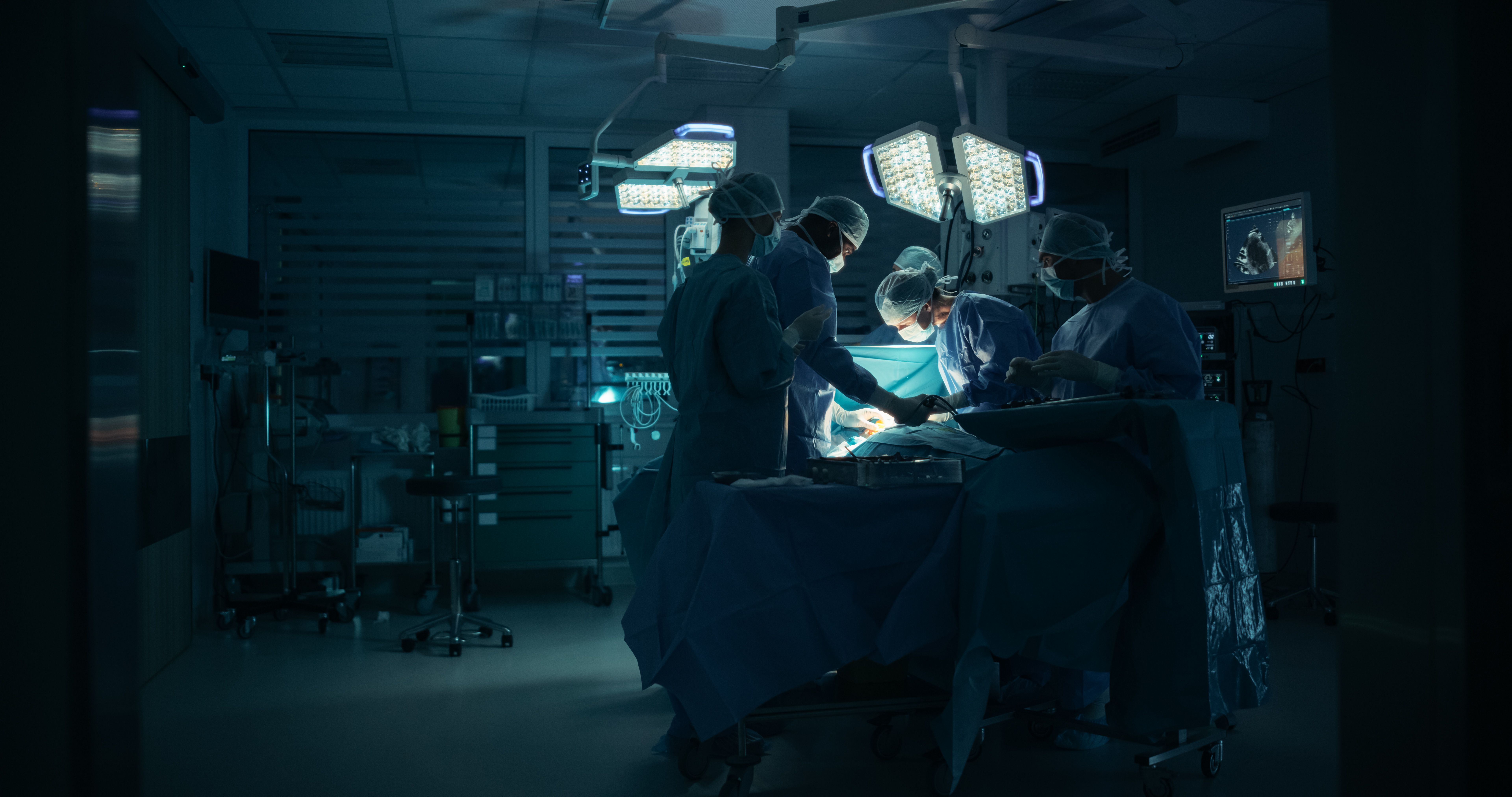 Skilled Male and Female Surgical Team Performing a Delicate Procedure with a Scalpel in a Technological Hospital Room. Group of Healthcare Professionals Collaborating Around the Operating Table