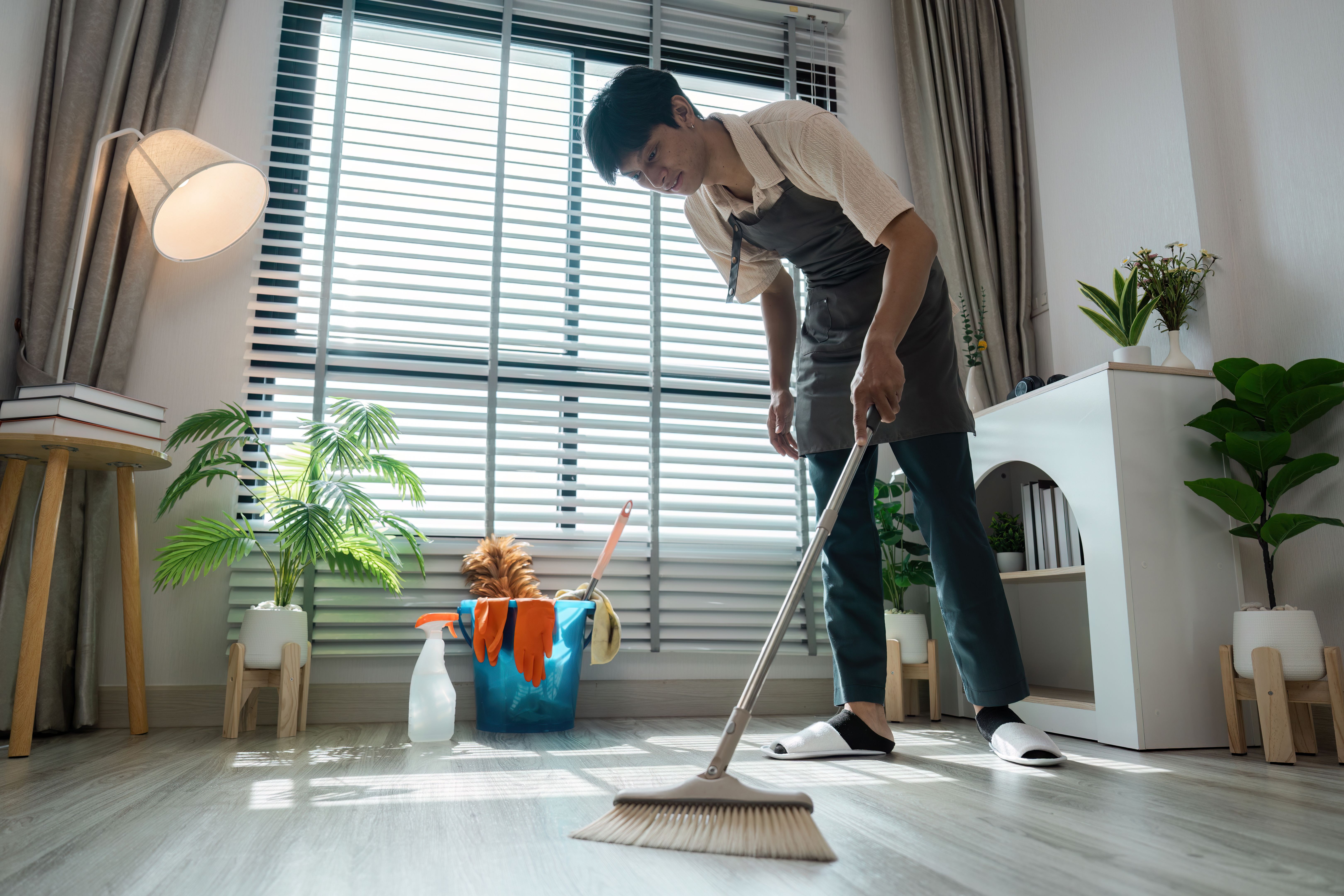 Home Cleaning and Organization. A skilled individual meticulously sweeping the floor, contributing to a well-maintained home environment. Home Cleaning and Organization. A skilled individual meticulously sweeping the floor, contributing to a well-maintained home environment.