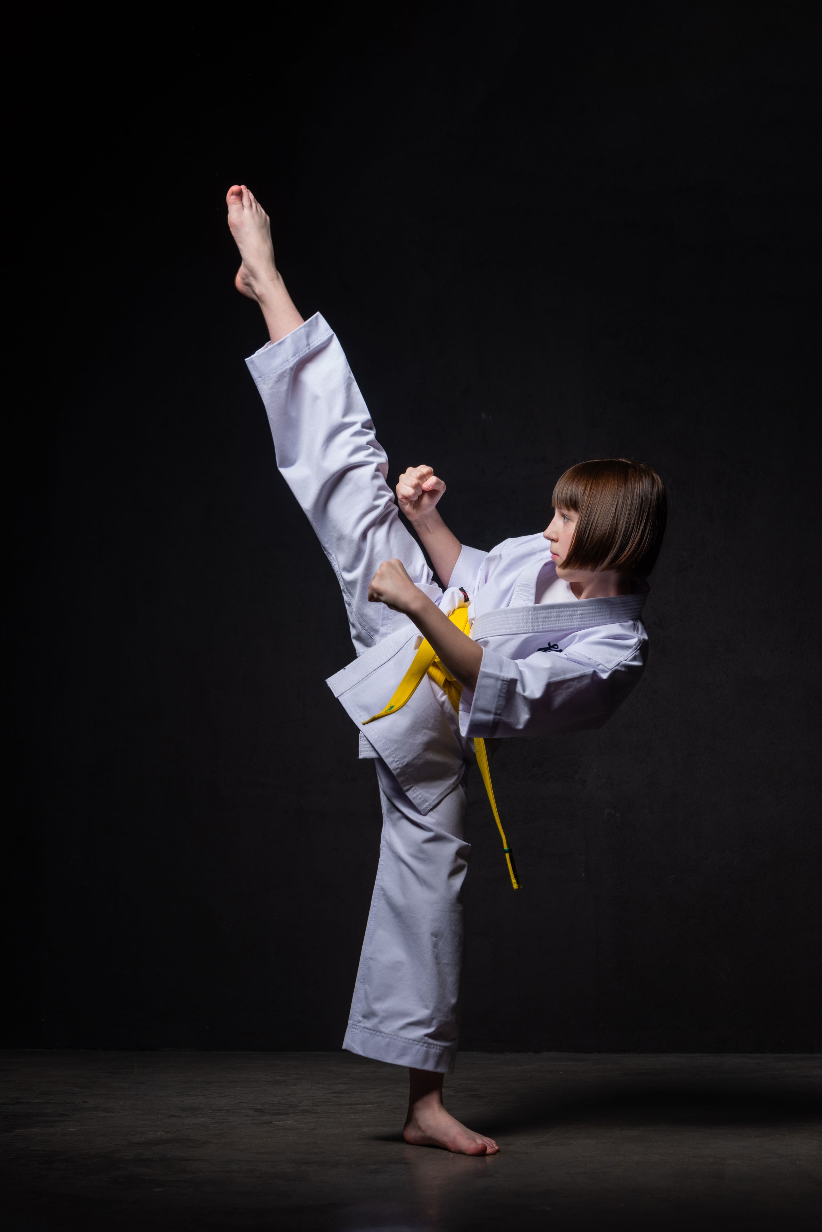 A karate girl trains in a kimono with punches and kicks