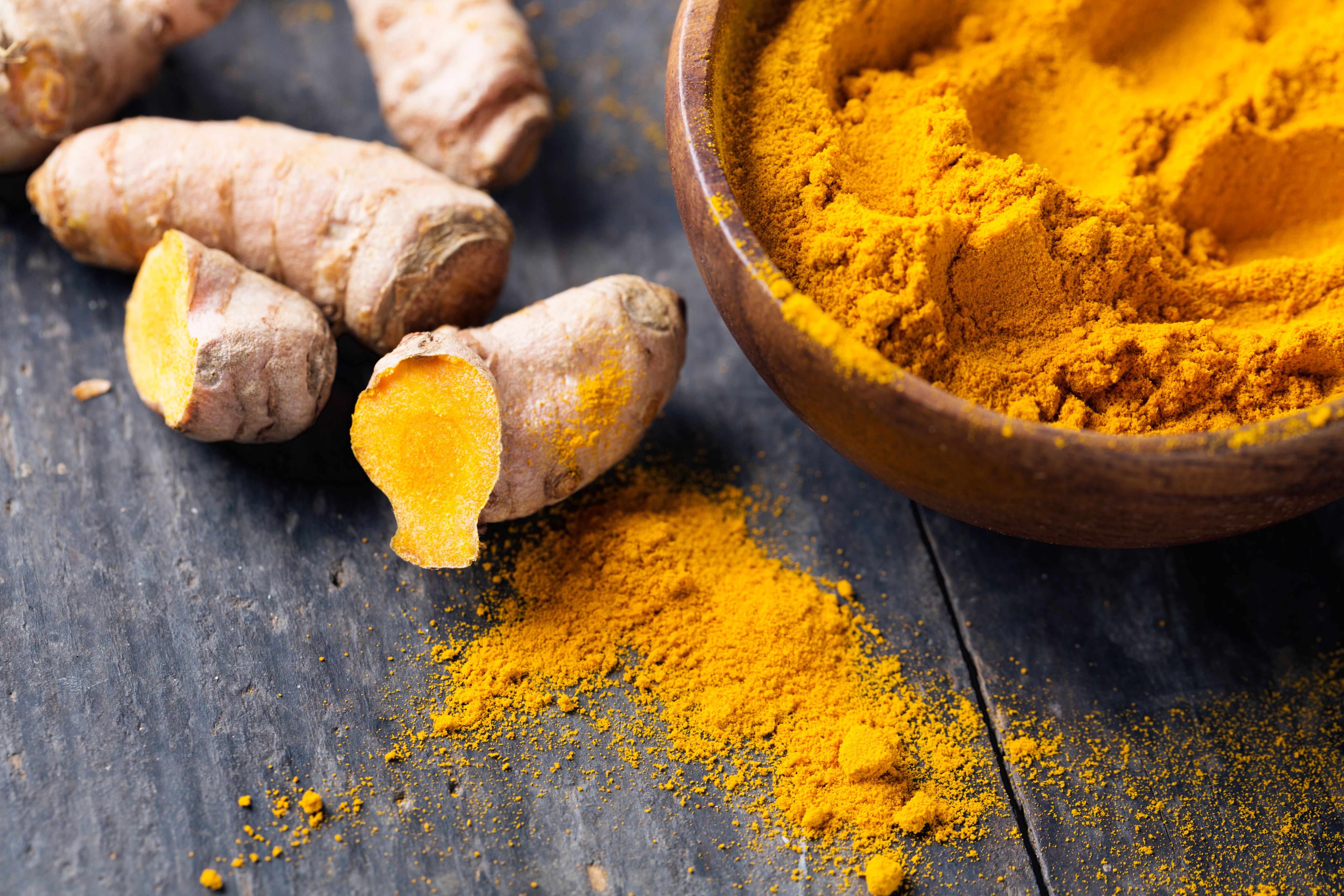 Spice: turmeric roots and powder on wood Spice: turmeric roots and powder on wood