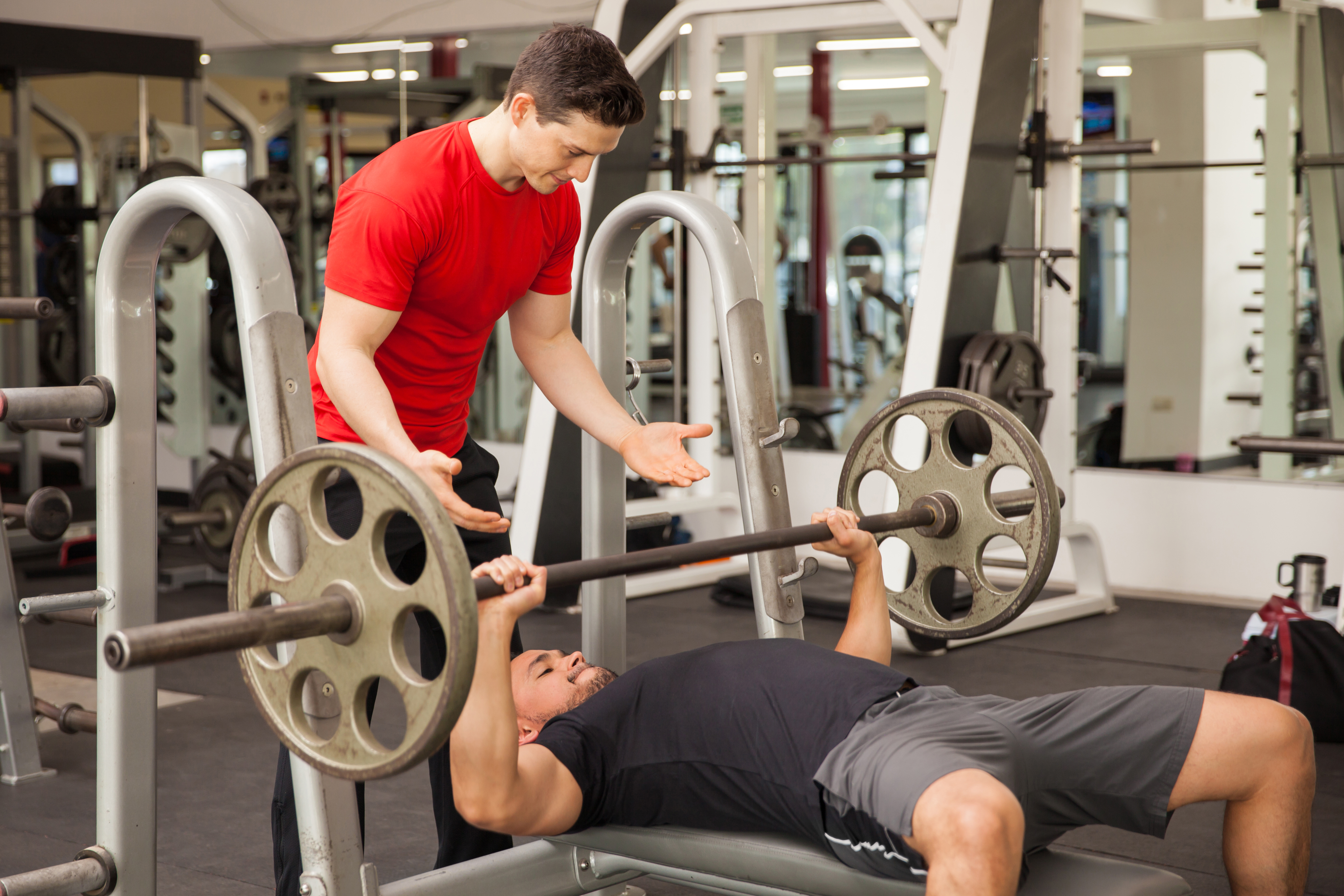 Young man spotting each other in a gym Young man spotting each other in a gym