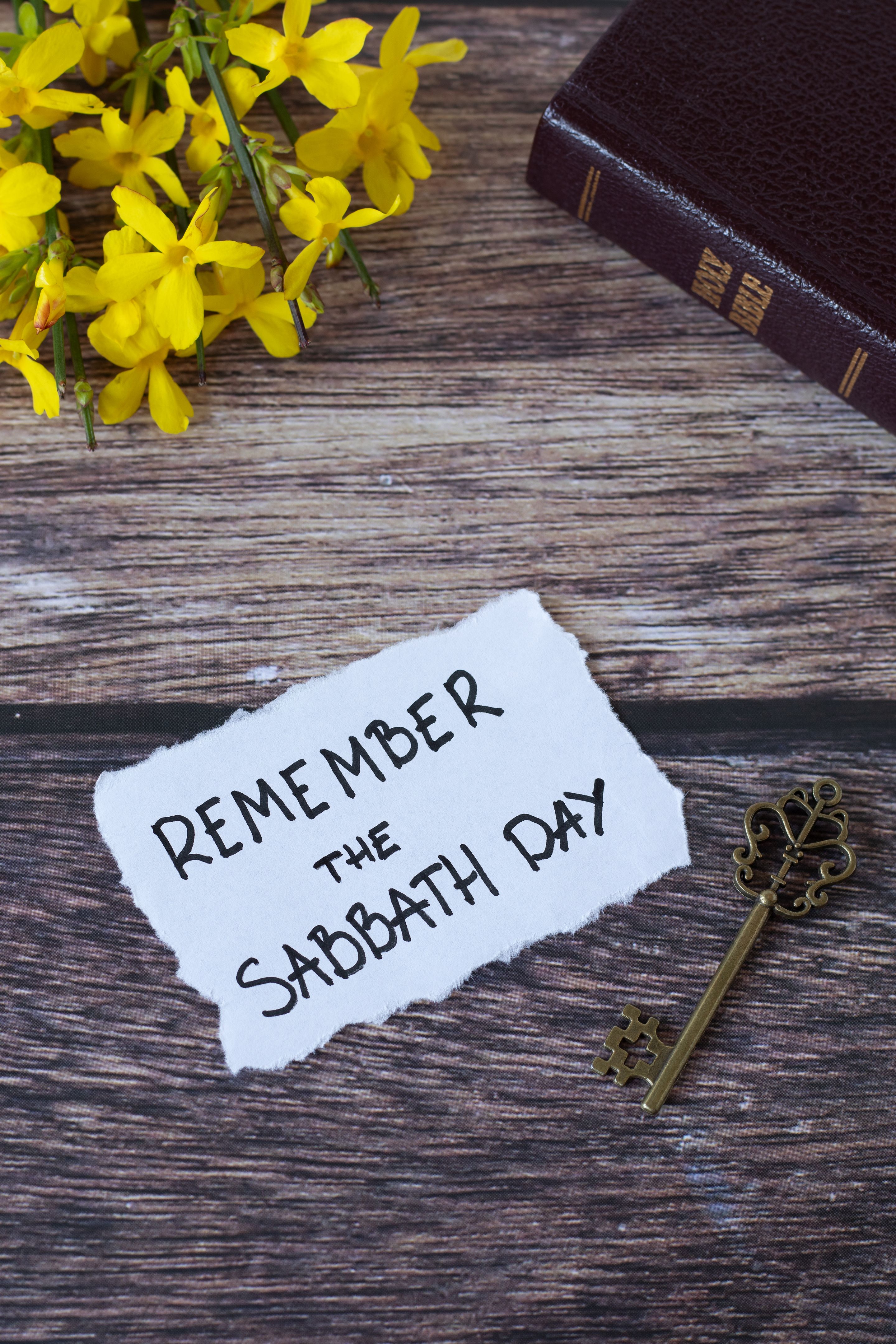 Remember the Sabbath Day, handwritten note with holy bible, antique key, and flowers on wooden table