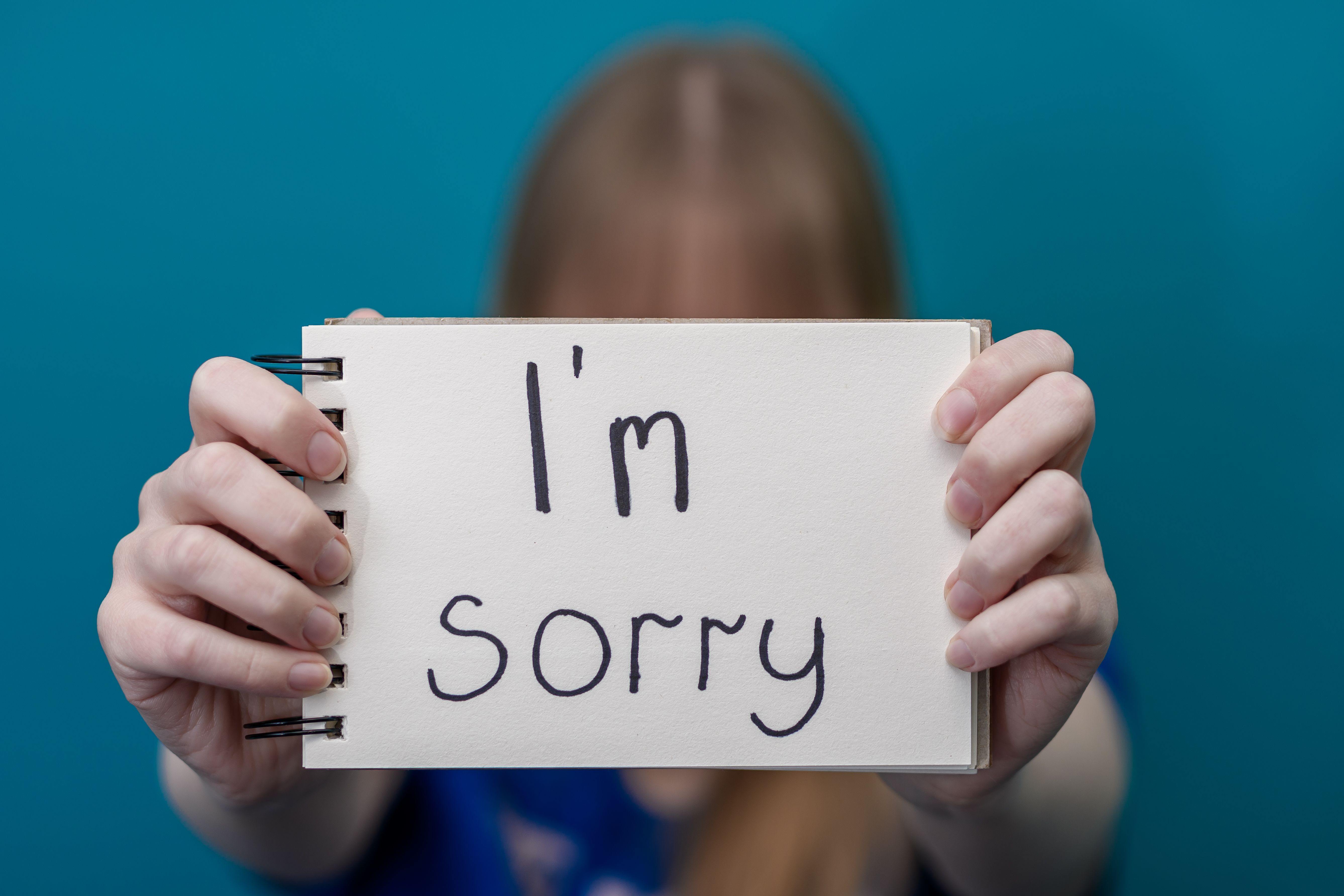 a woman holds a card with the words sorry in her hands a woman holds a card with the words sorry in her hands