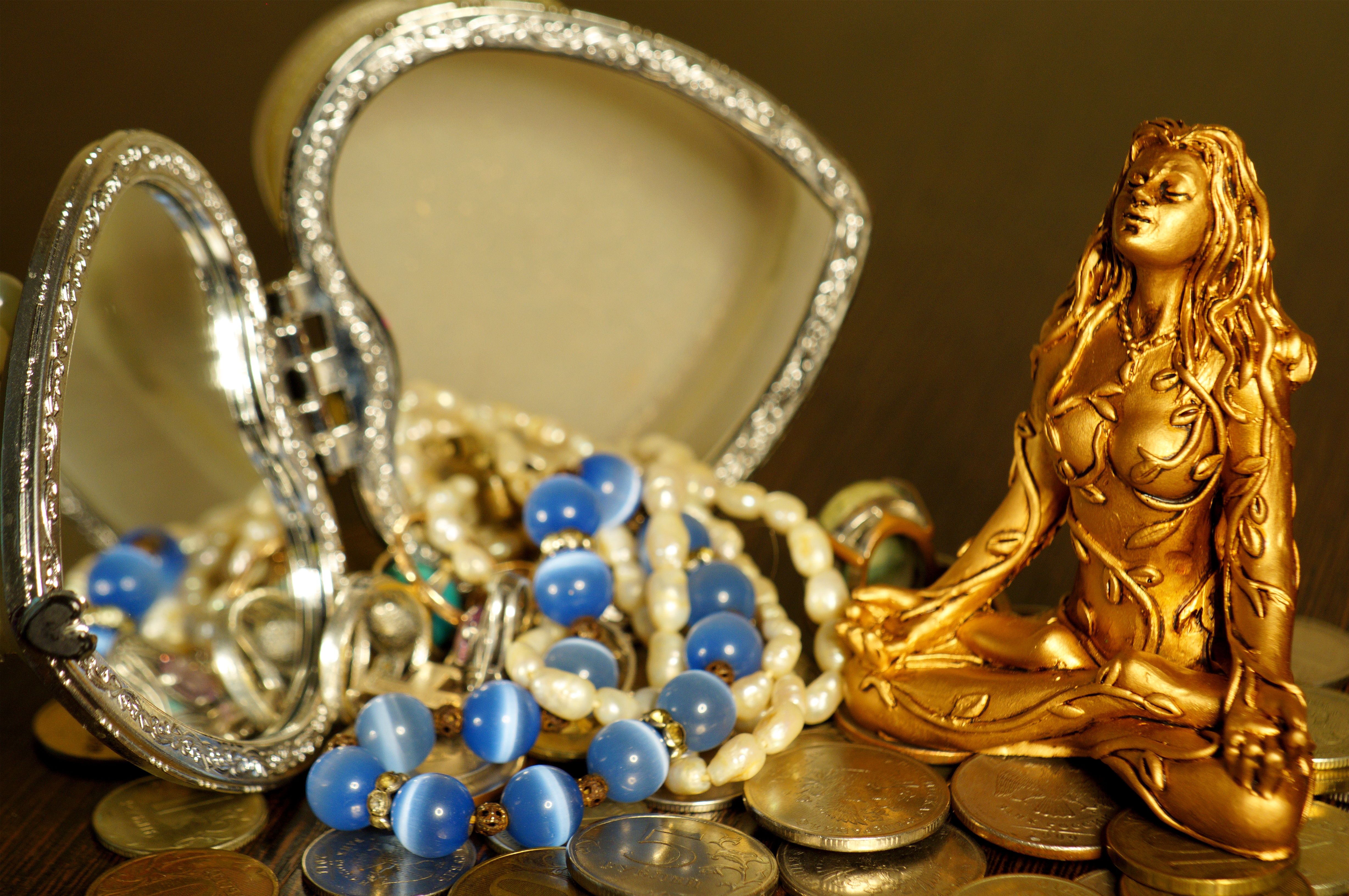 A female Buddha statuette with jewelry and coins.