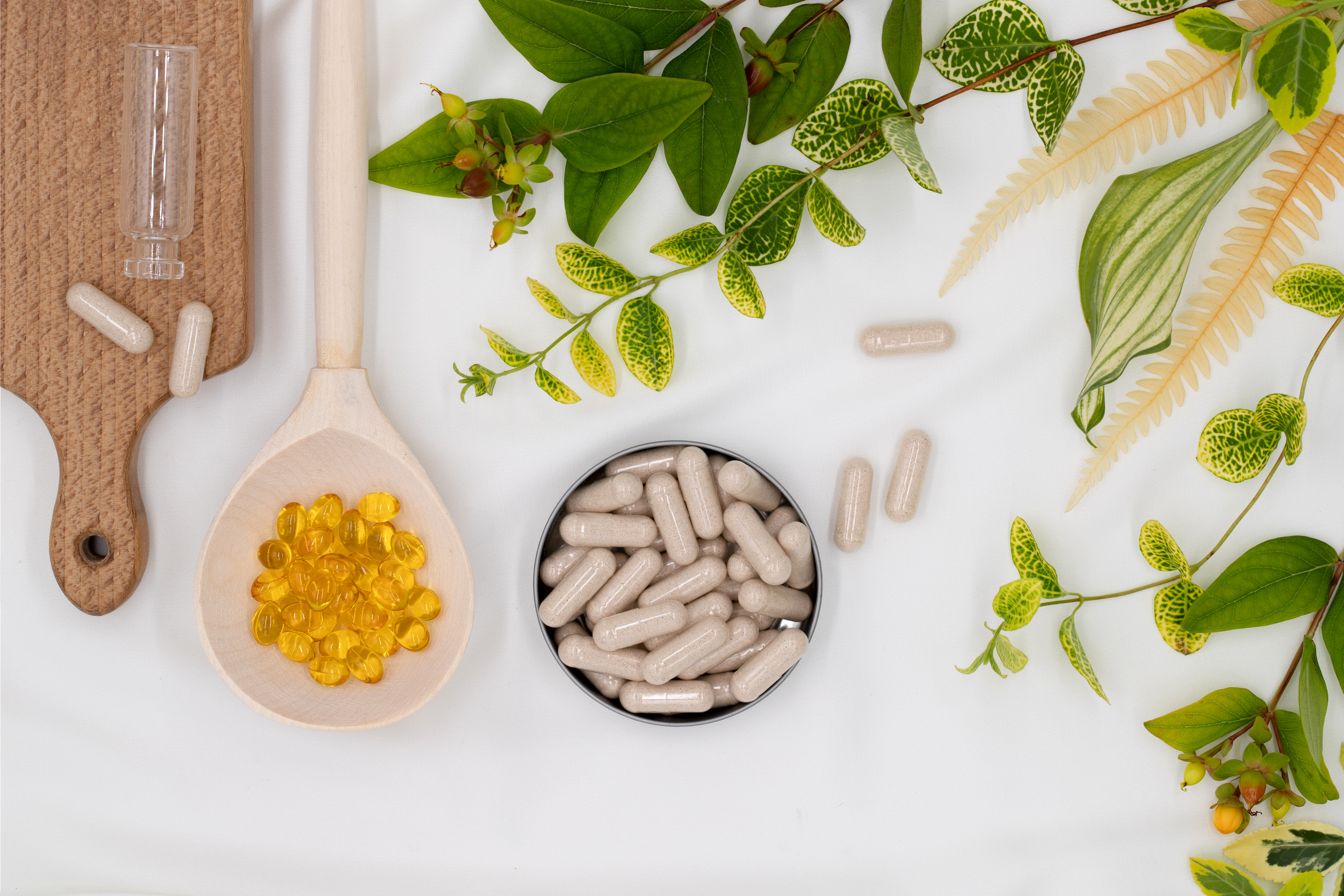 Capsules of vitamins and oils, medicinal herbs for skin care and  healthy lifestyle, on white background, top view