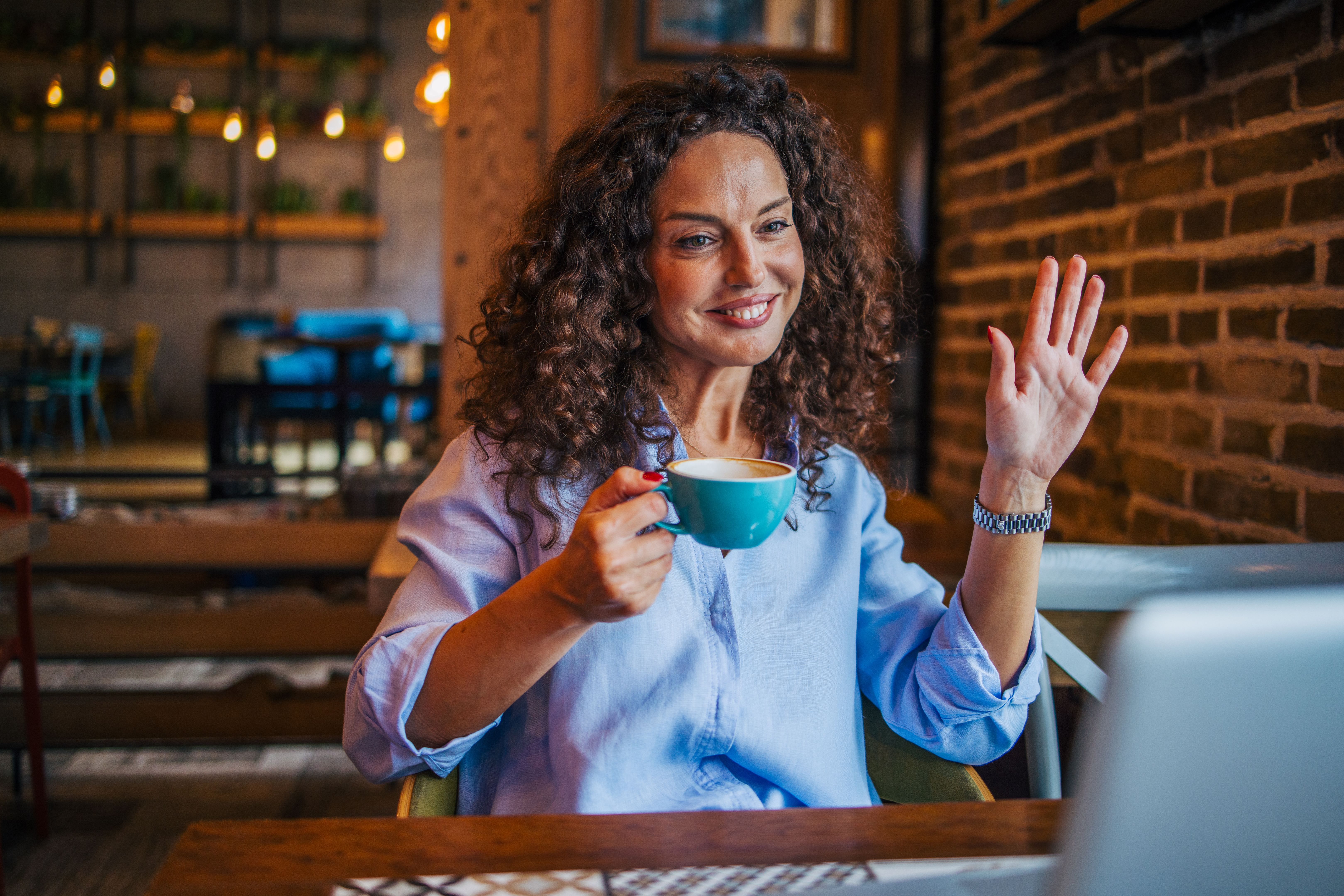 A curly hair mature woman enjoy in cafe. mature woman using laptop.