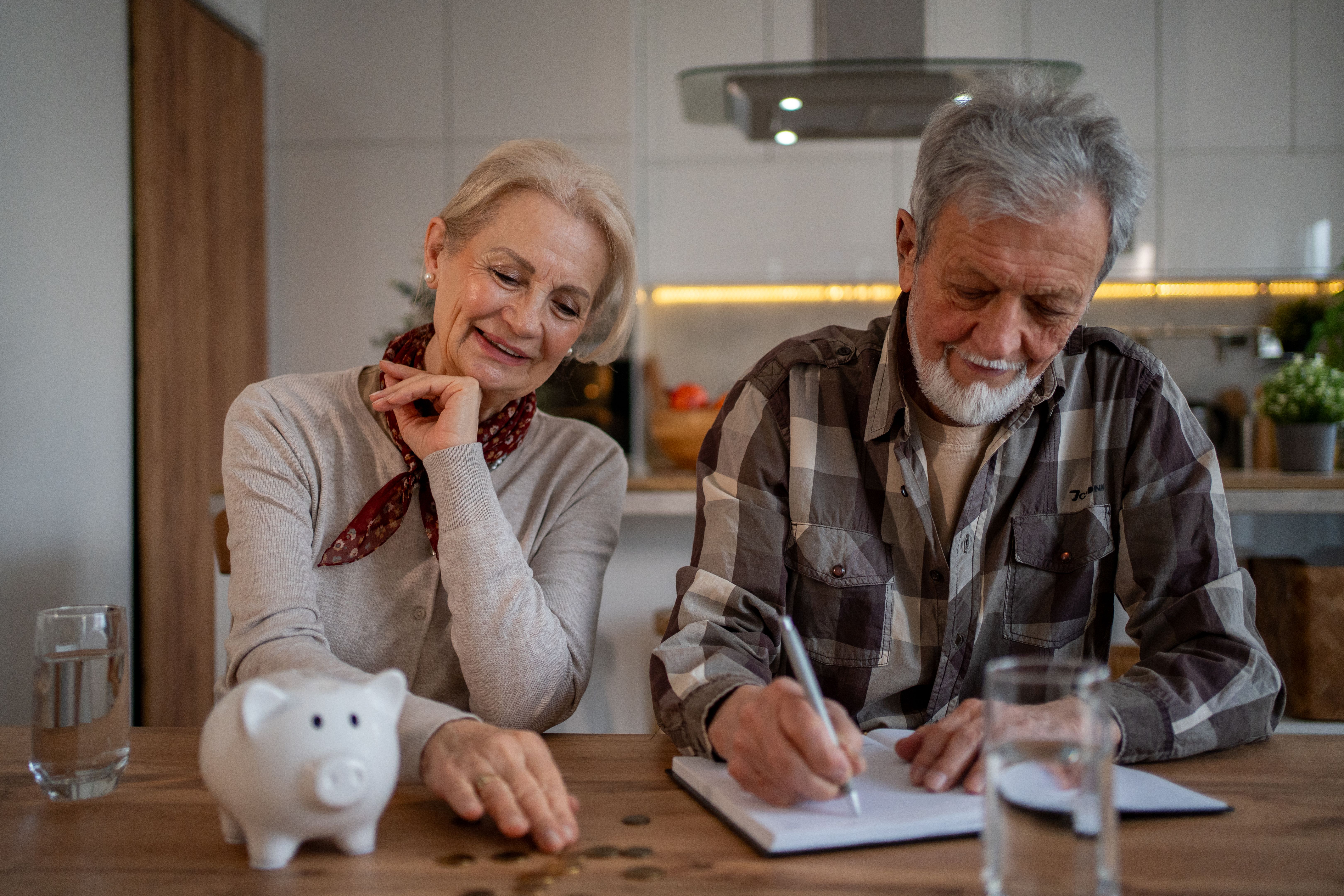 Senior couple managing home finances and savings with piggy bank