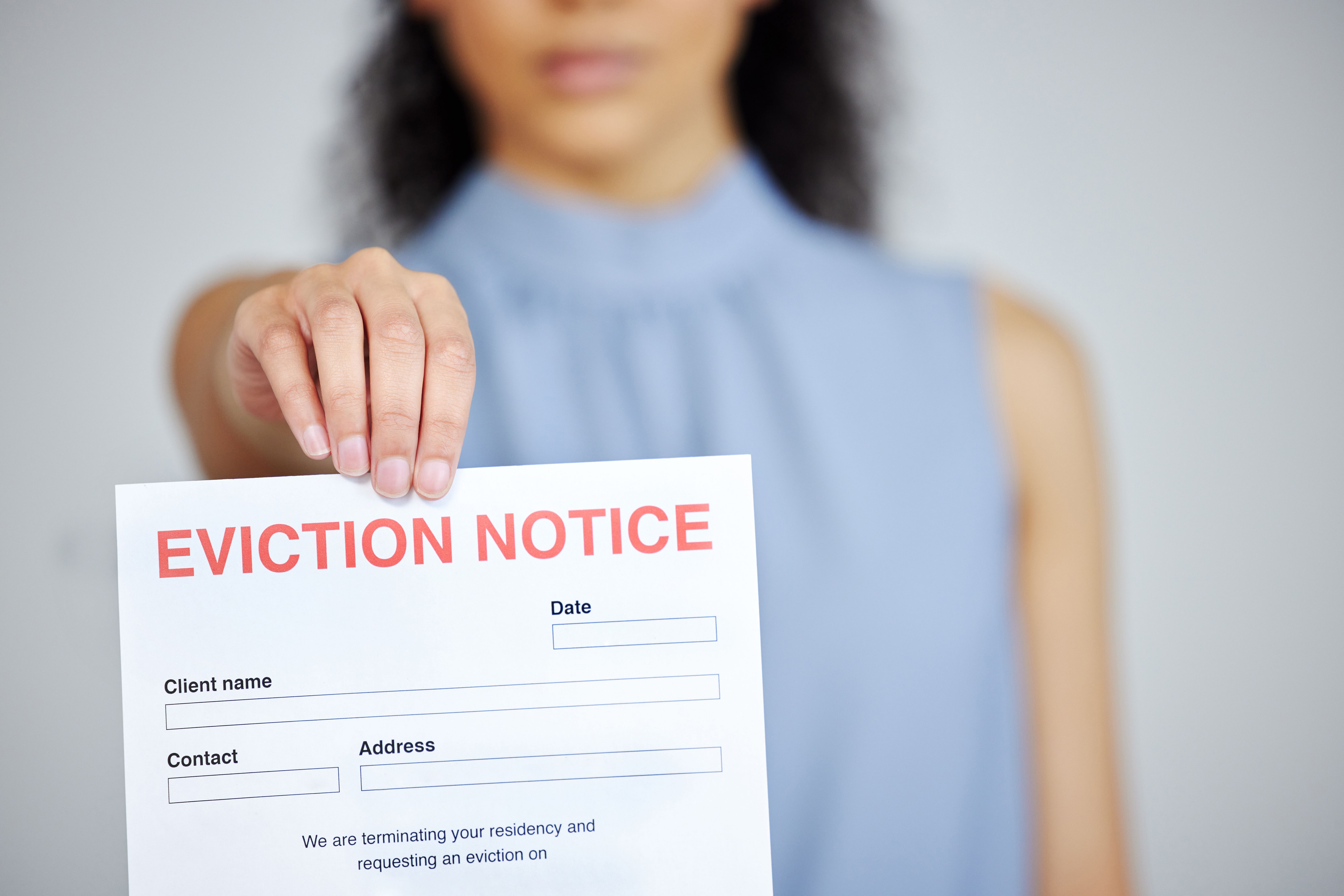 Cropped shot of an unrecognisable woman standing alone and holding an eviction notice at home