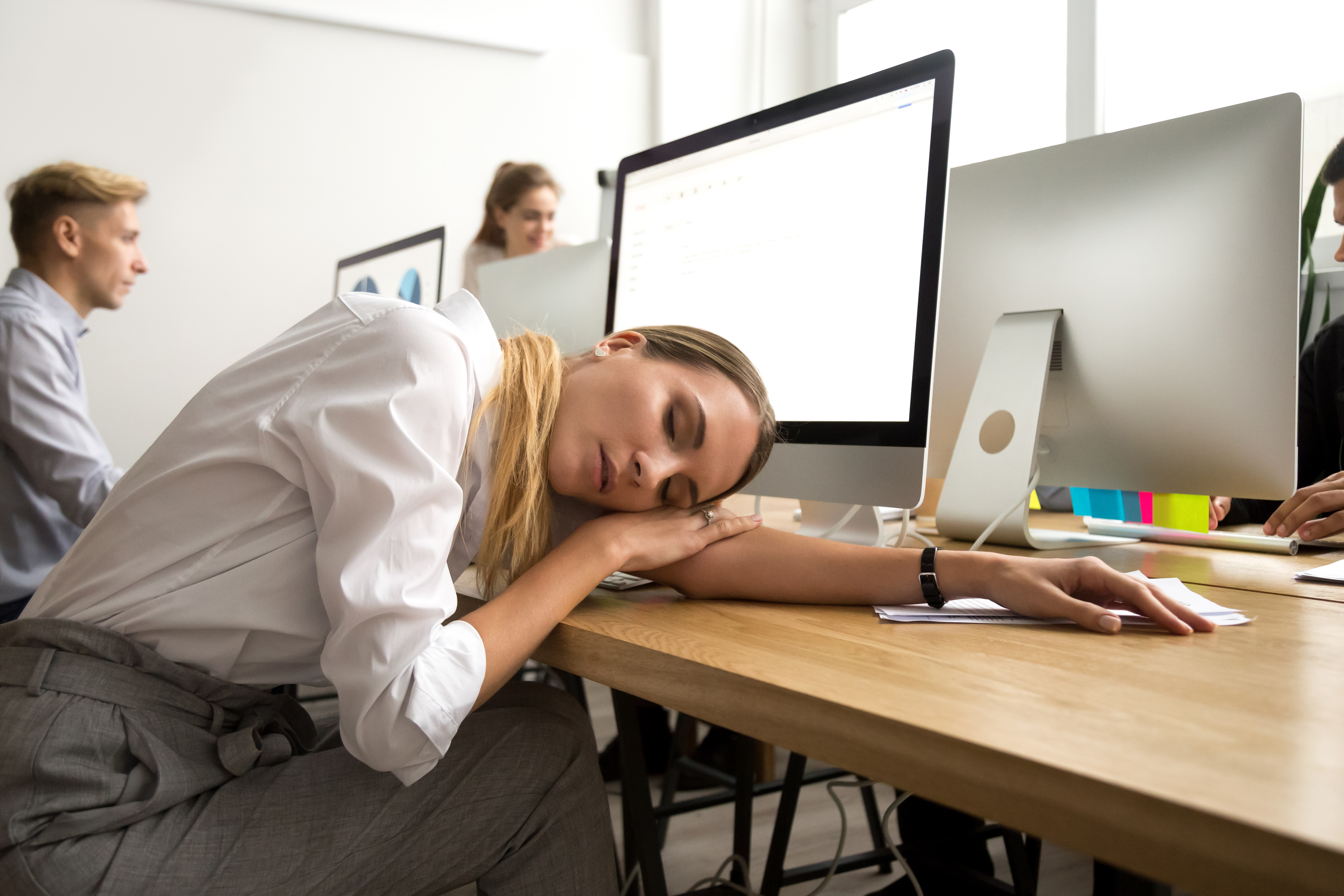 Tired or bored female employee lying asleep at office workplace Tired or bored female employee lying asleep at office workplace