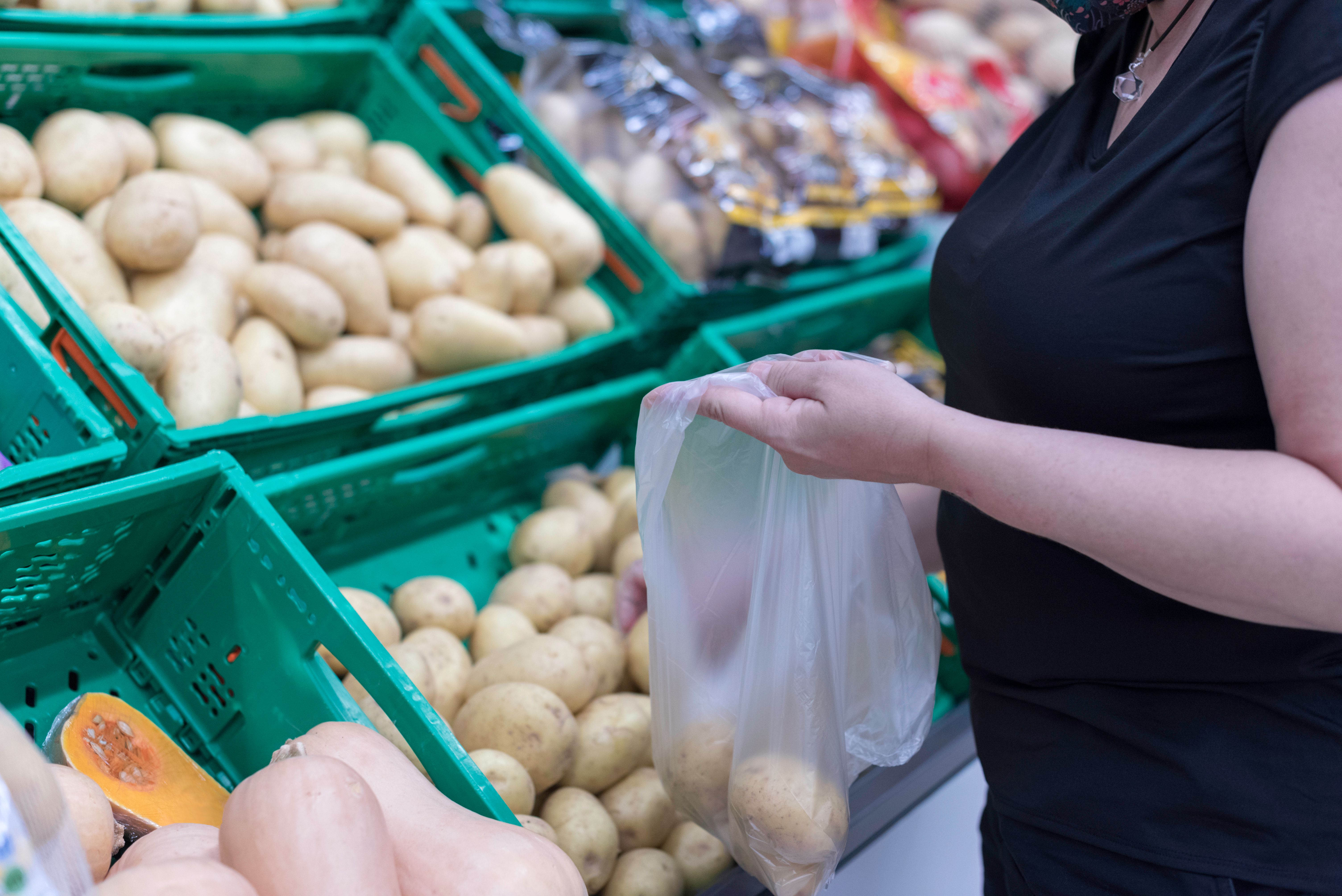 Woman choosing potatoes to buy in a supermarket. Organic Store.