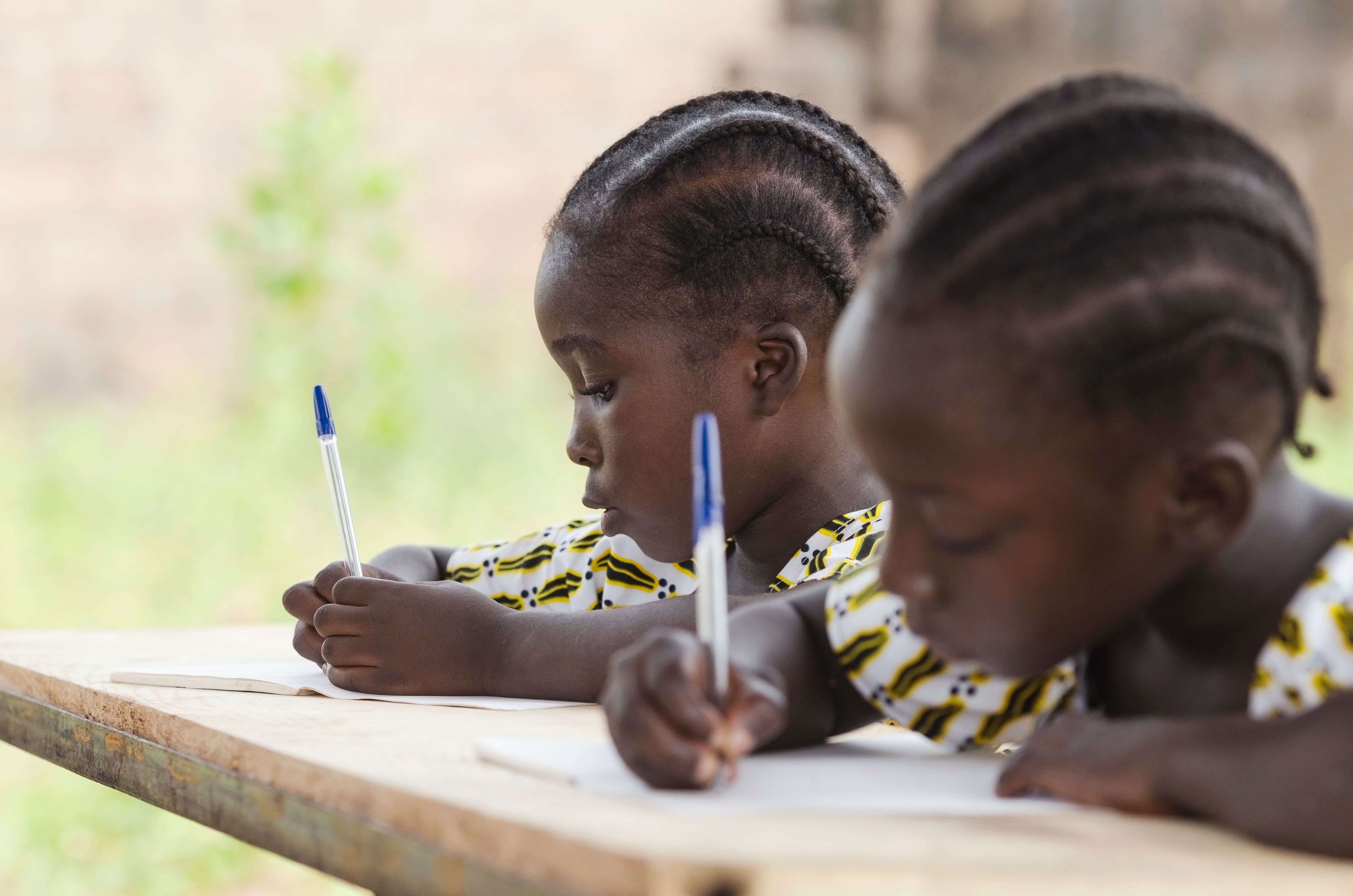 Close-Up Of Girls Writing In Book