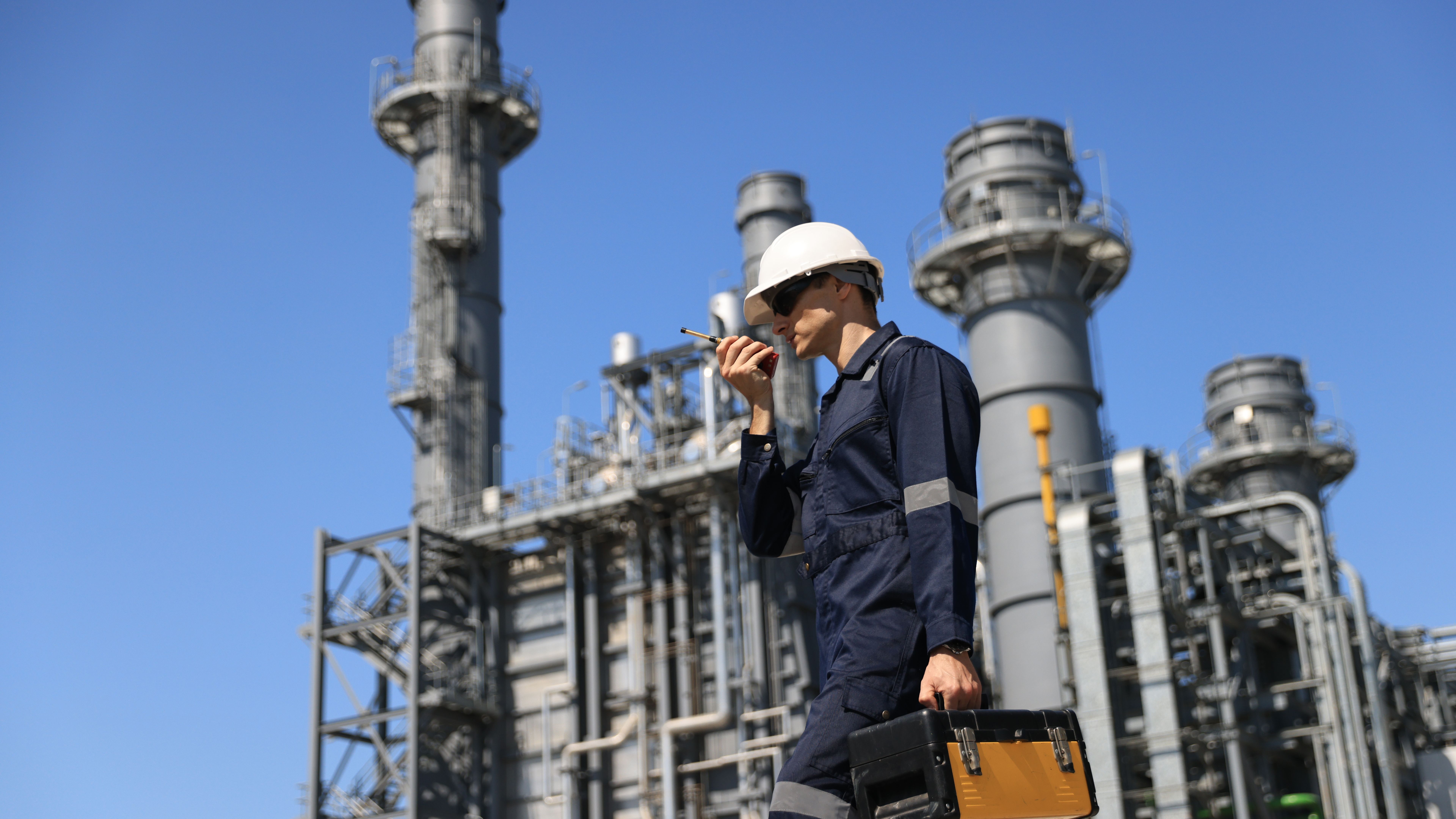 Maintenance Engineer using a walkie-talkie  and hold toolbox working at a thermal power plant