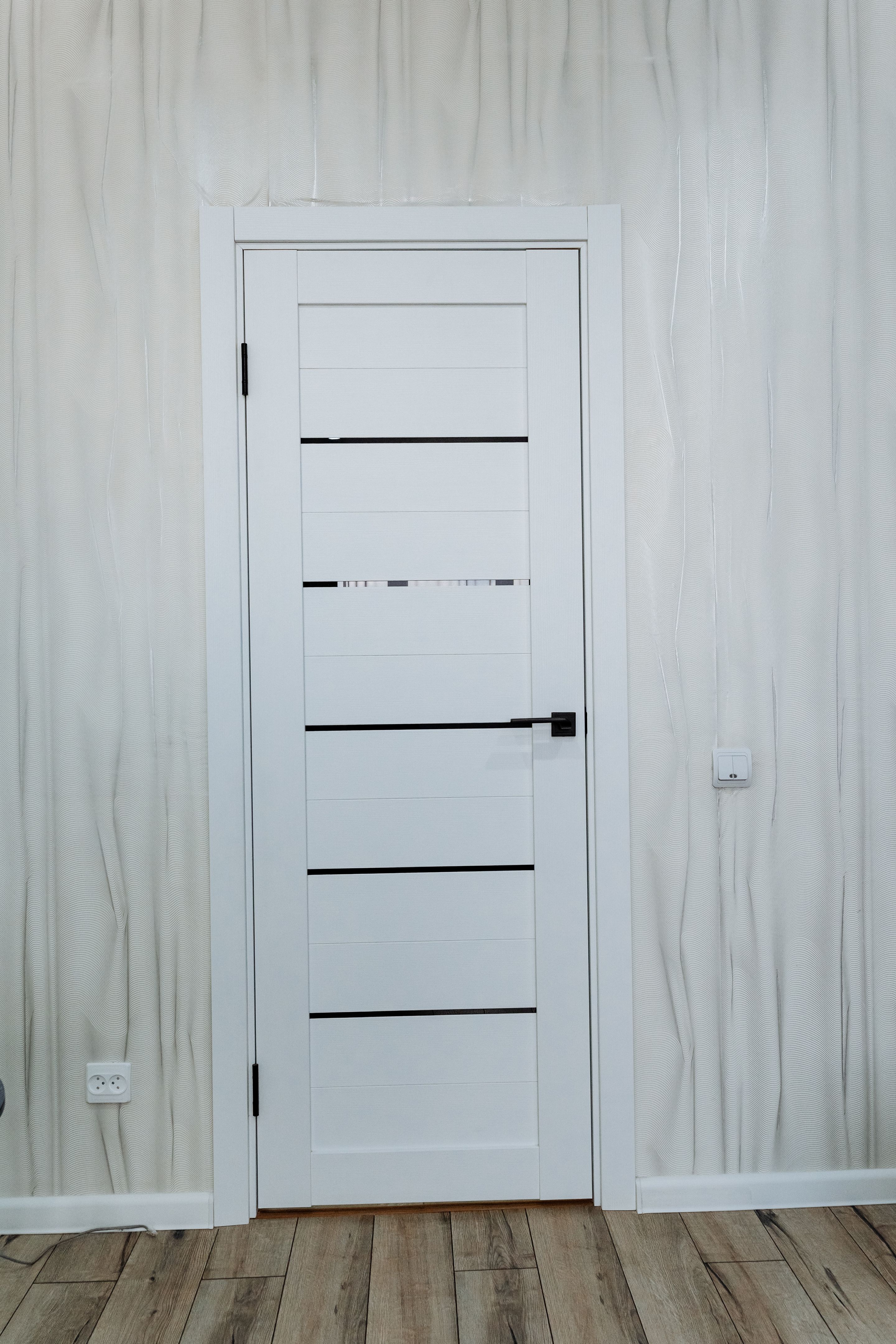 A room with a crafted wooden floor and a white door A room with a crafted wooden floor and a white door