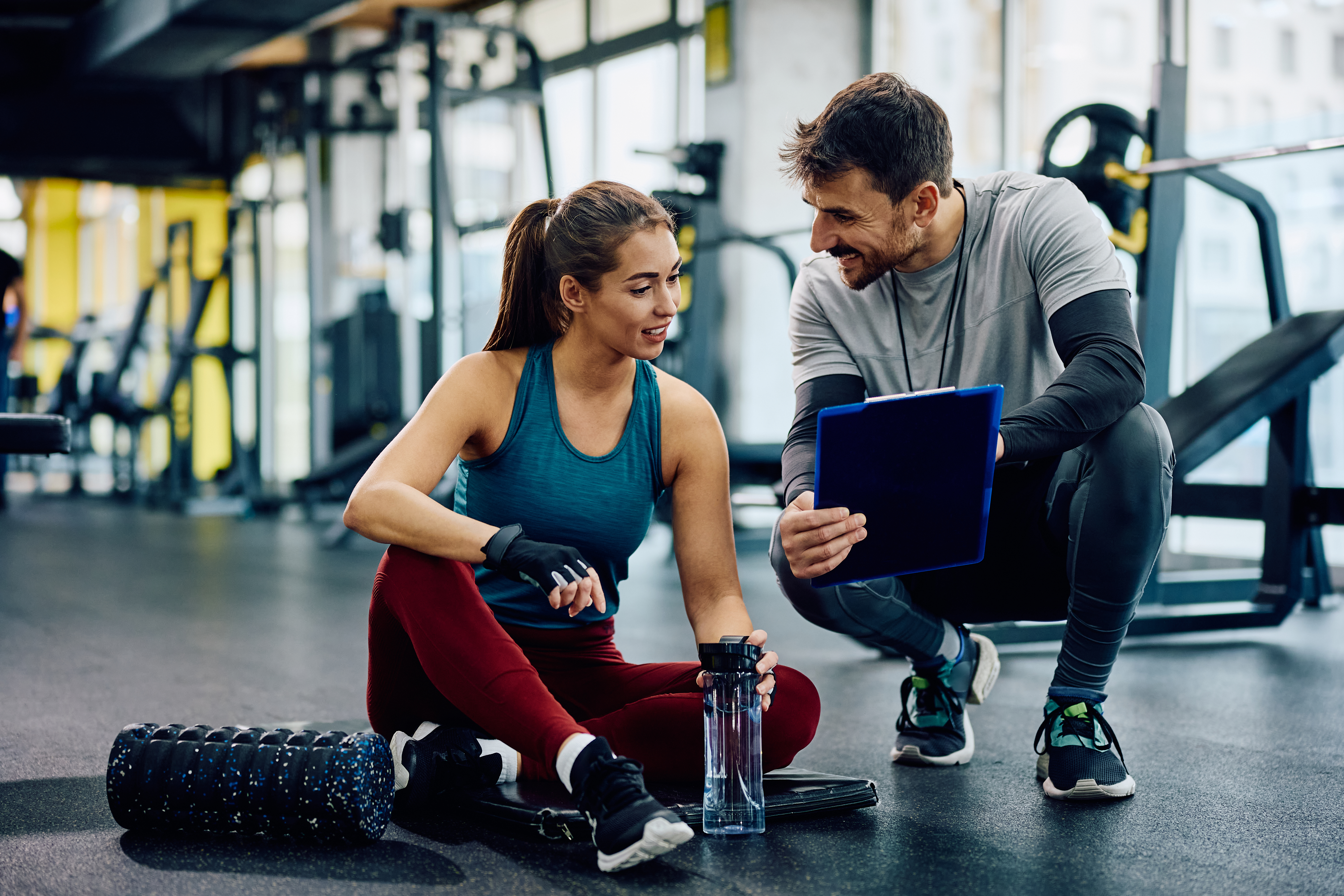 Personal instructor and athletic woman going through exercise plans in a gym.