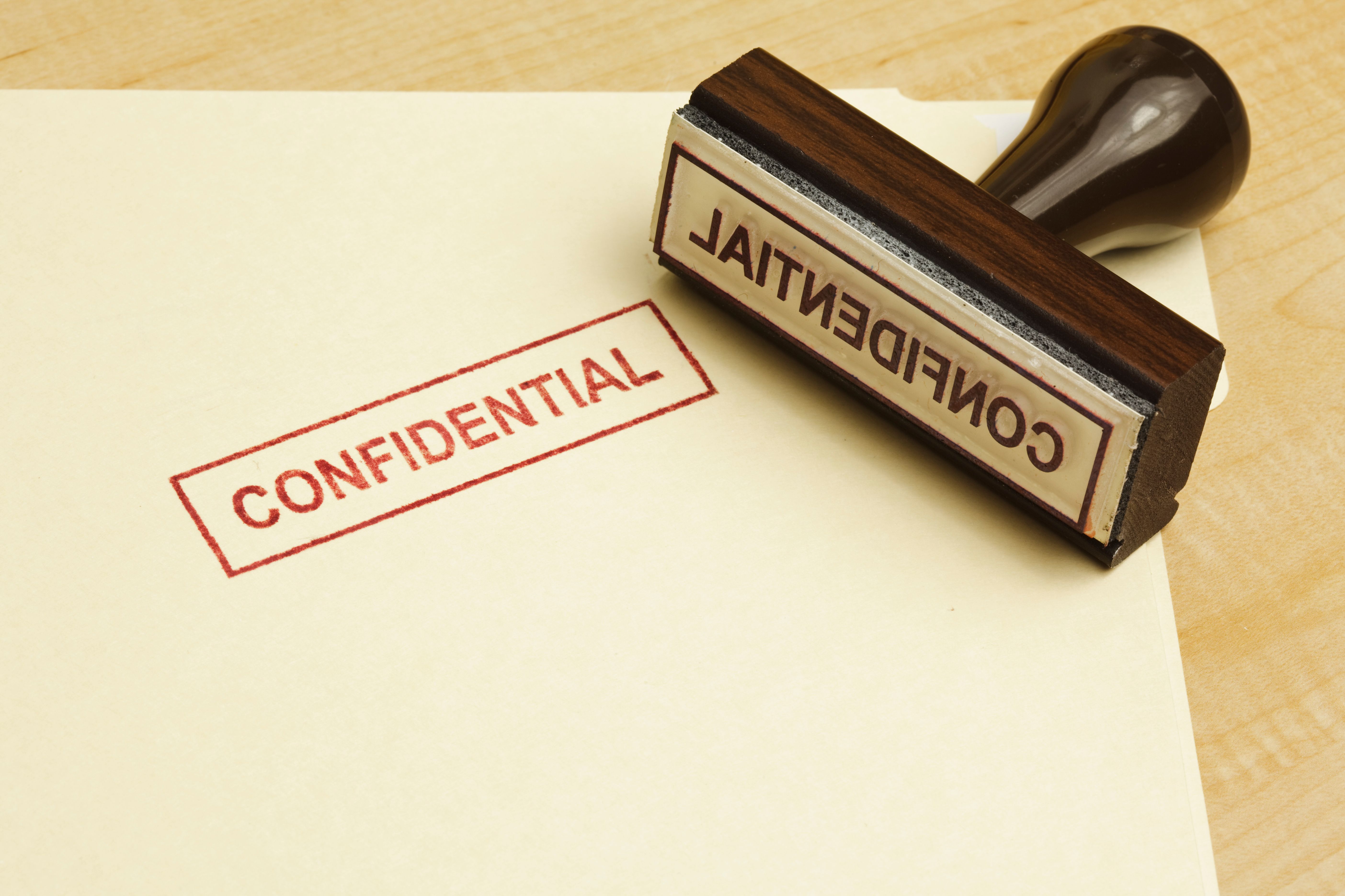 Manilla folder stamped CONFIDENTIAL with rubber stamp next to it