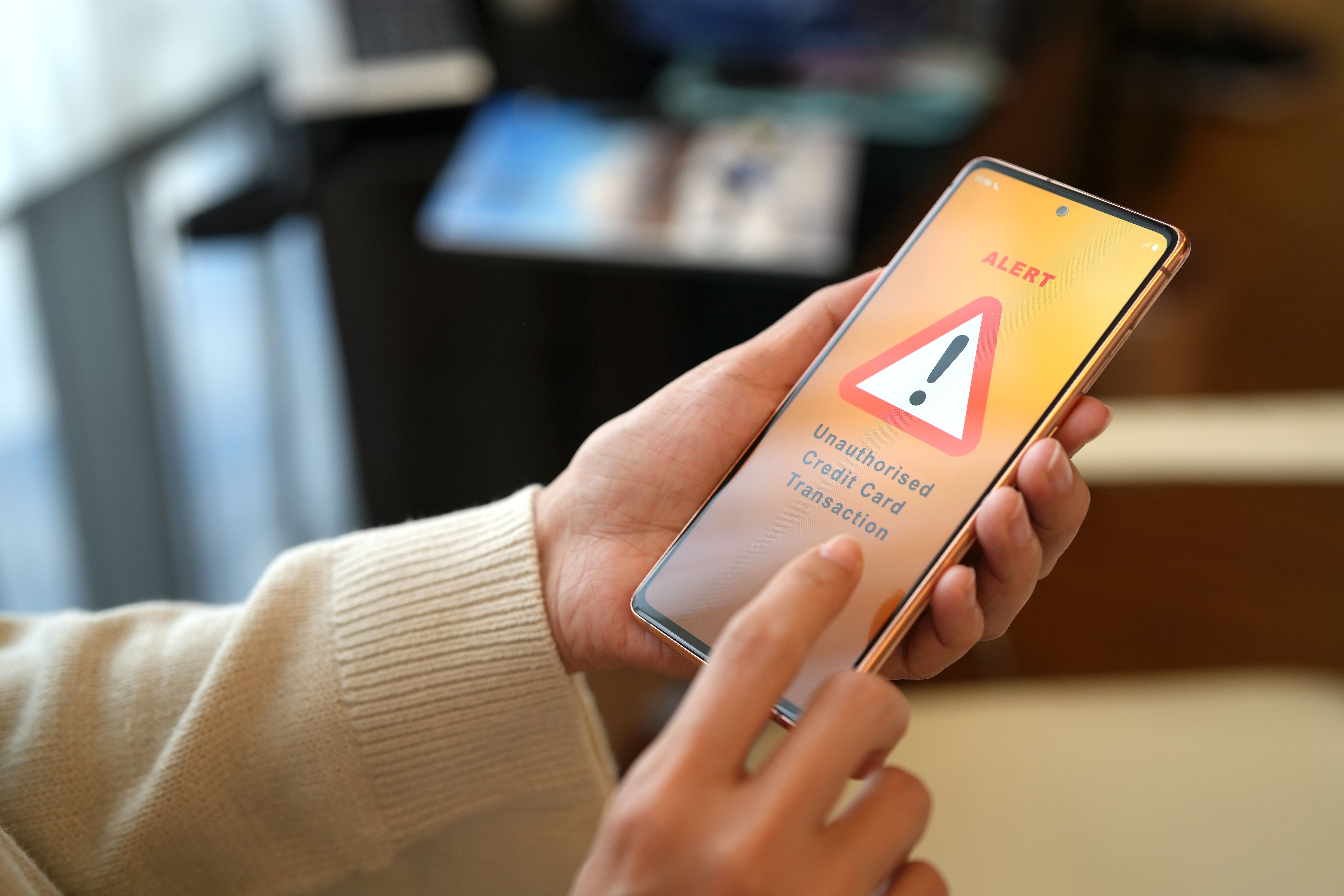 Cropped image of a woman receiving an alert message from bank regarding unauthorised credit card transaction on her smartphone