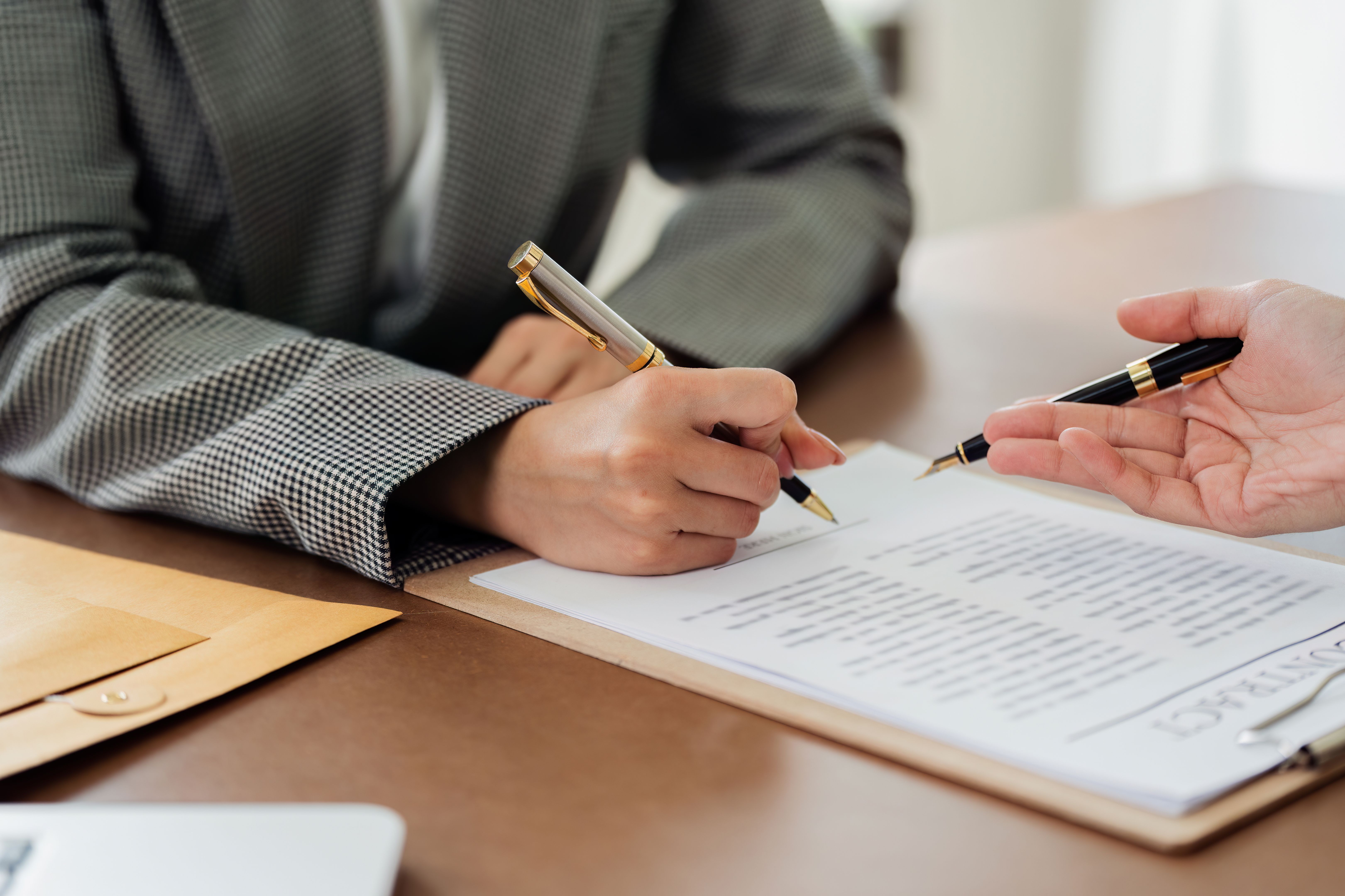 A woman is signing a document with a pen