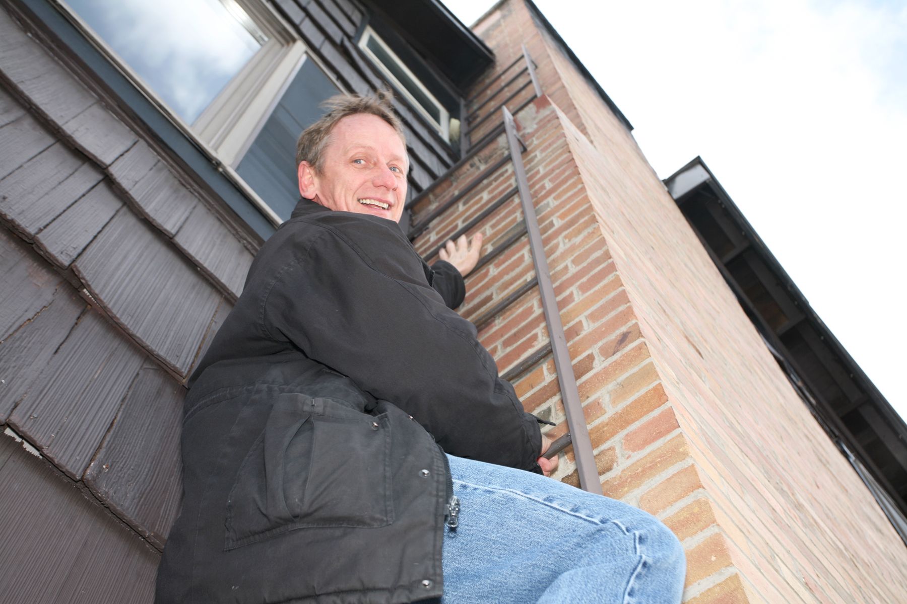 Man climbing up a fire escape ladder