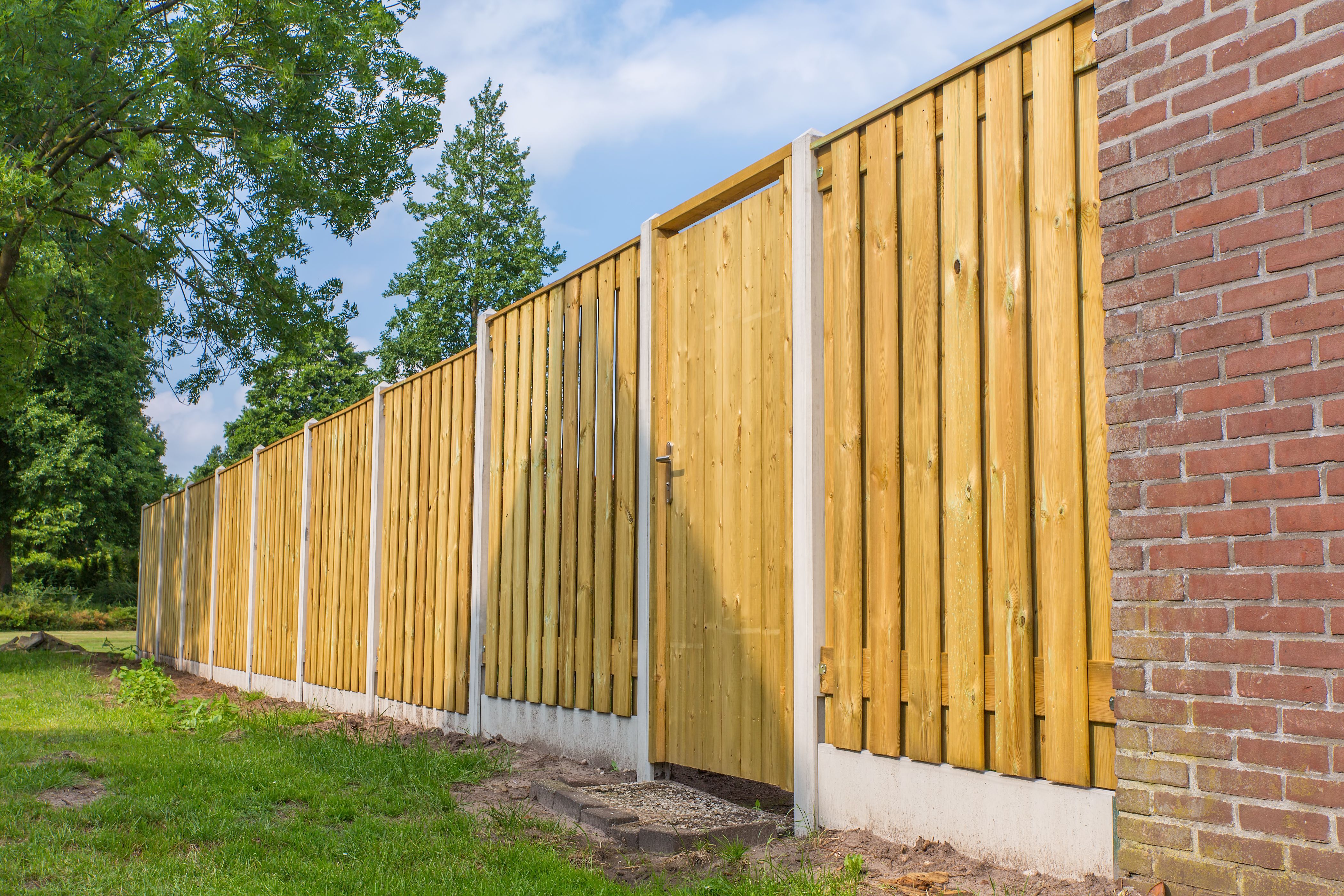 New wooden fence construction with brick wall