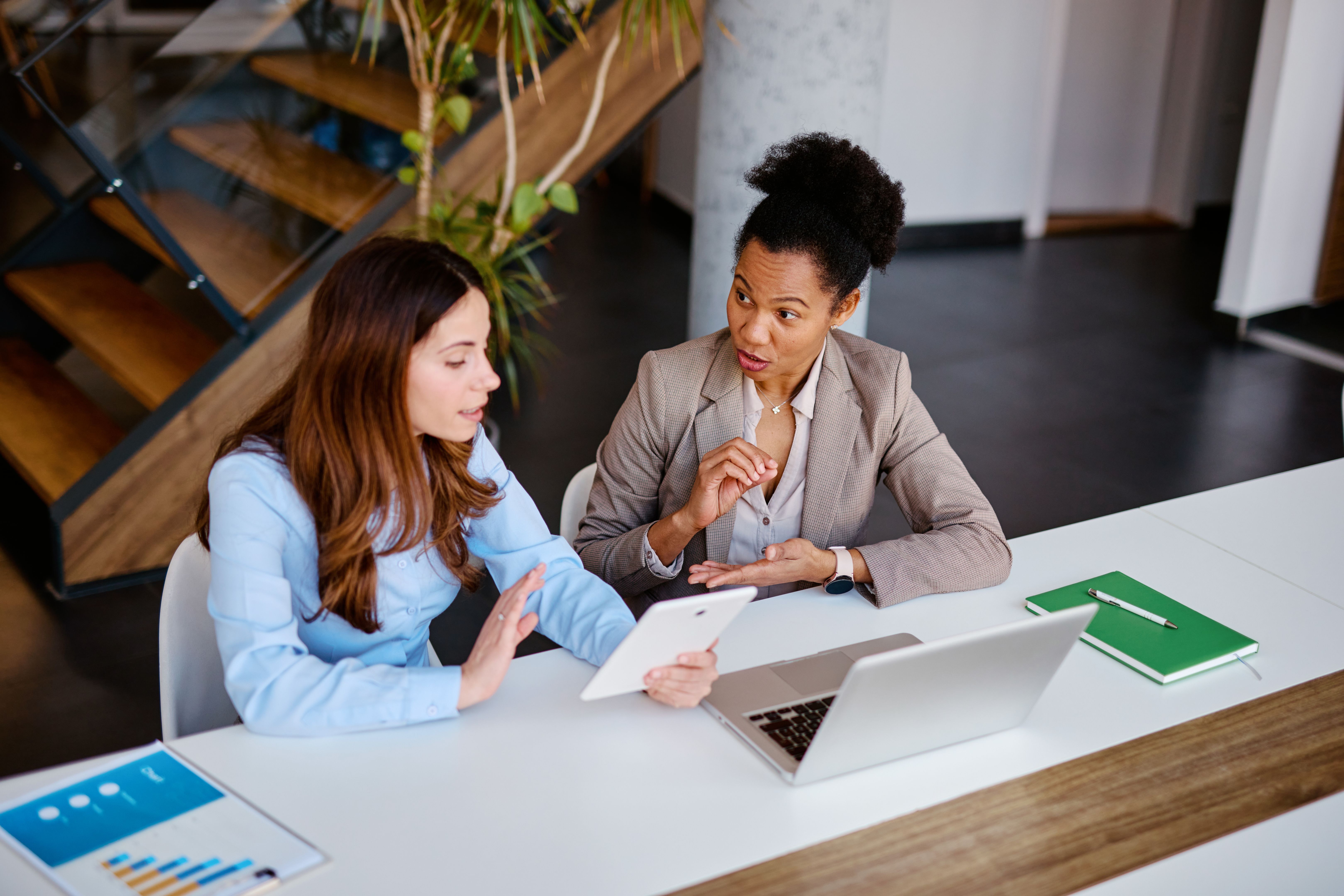 Businesswomen discussing over digital tablet in modern office Businesswomen discussing over digital tablet in modern office