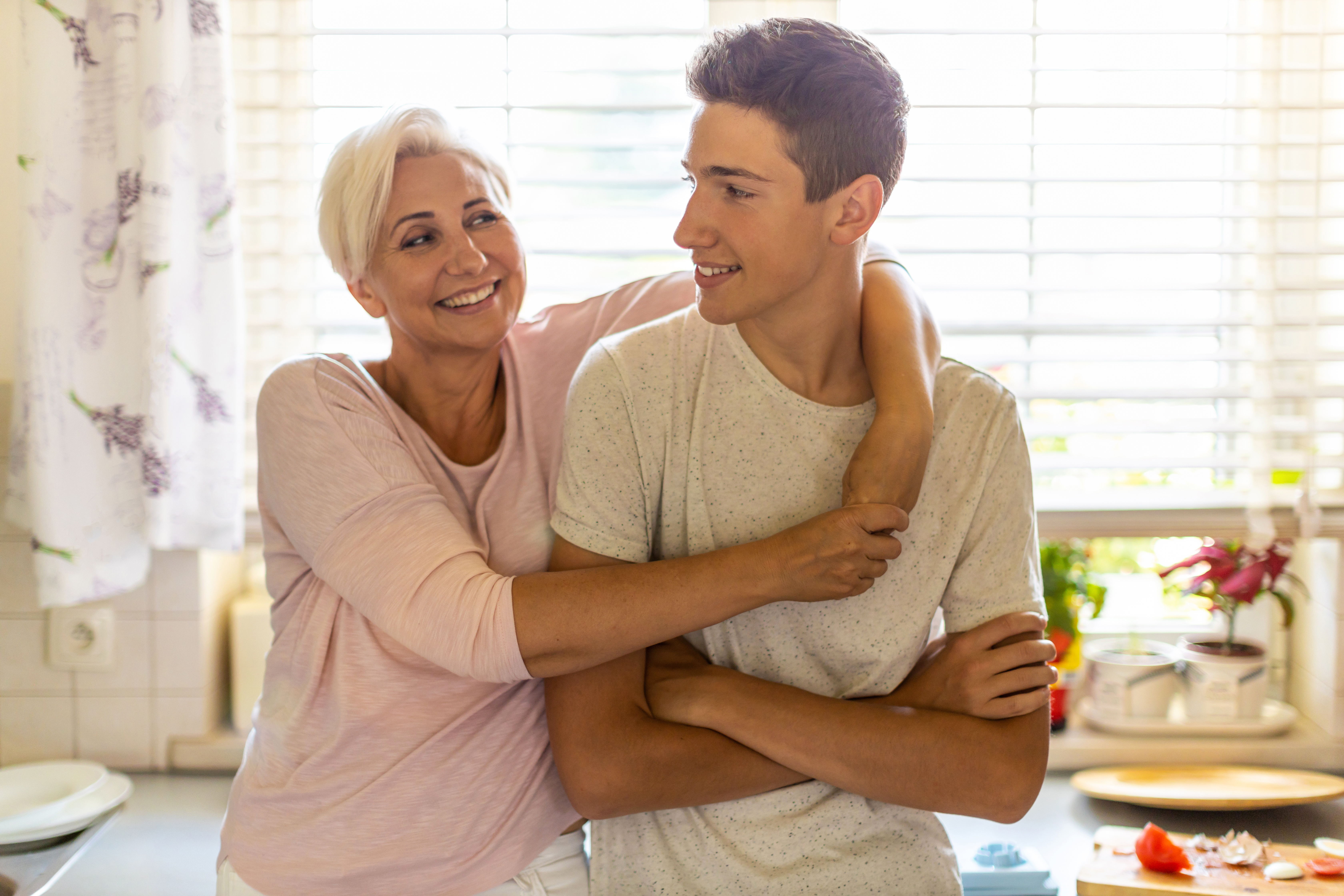 Mother hugging her teenage son in the kitchen Mother hugging her teenage son in the kitchen