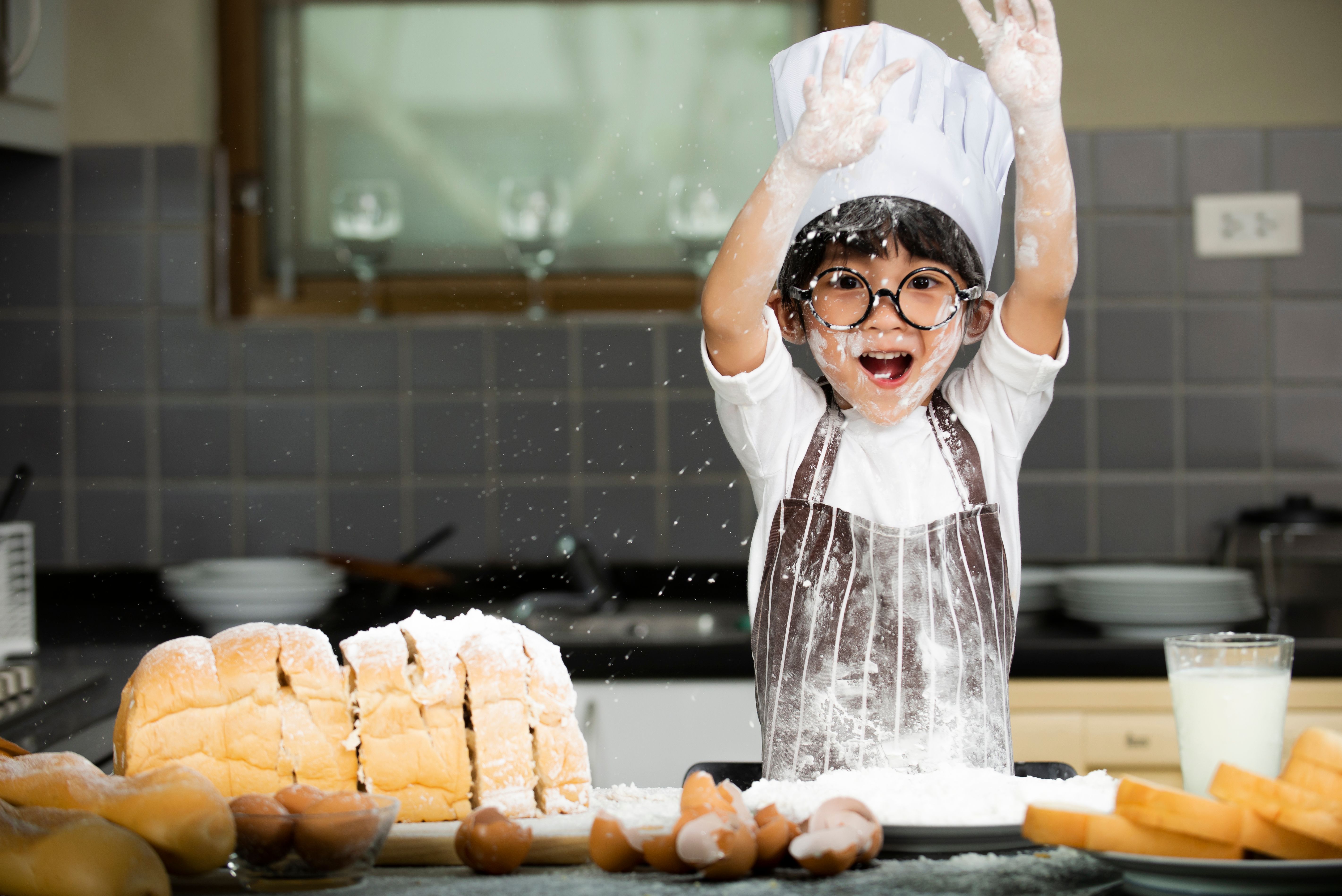 asian little boy in apron preparing baking the dough in kitchen room at home asian little boy in apron preparing baking the dough in kitchen room at home