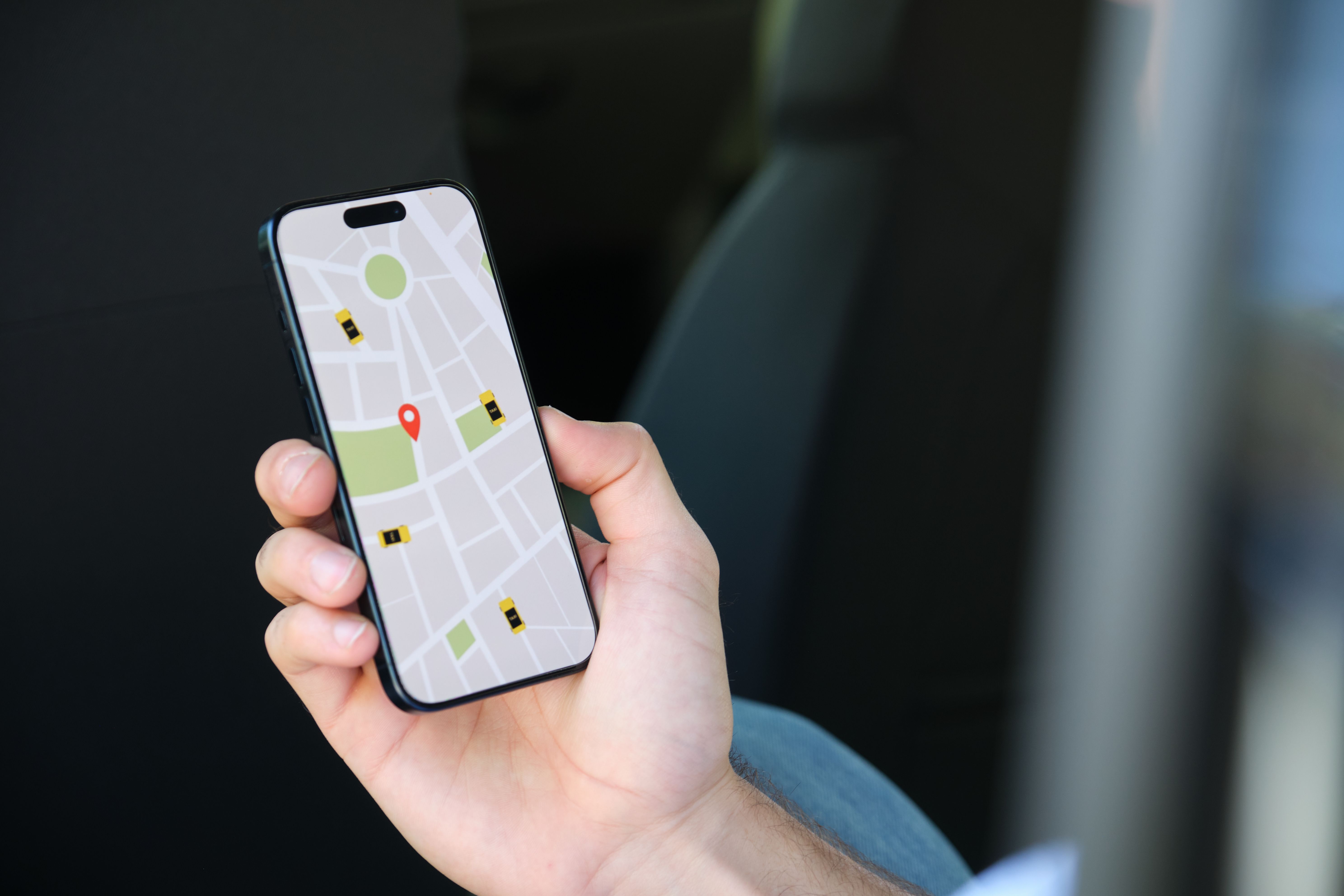 Businessman searching taxi on mobile phone inside car