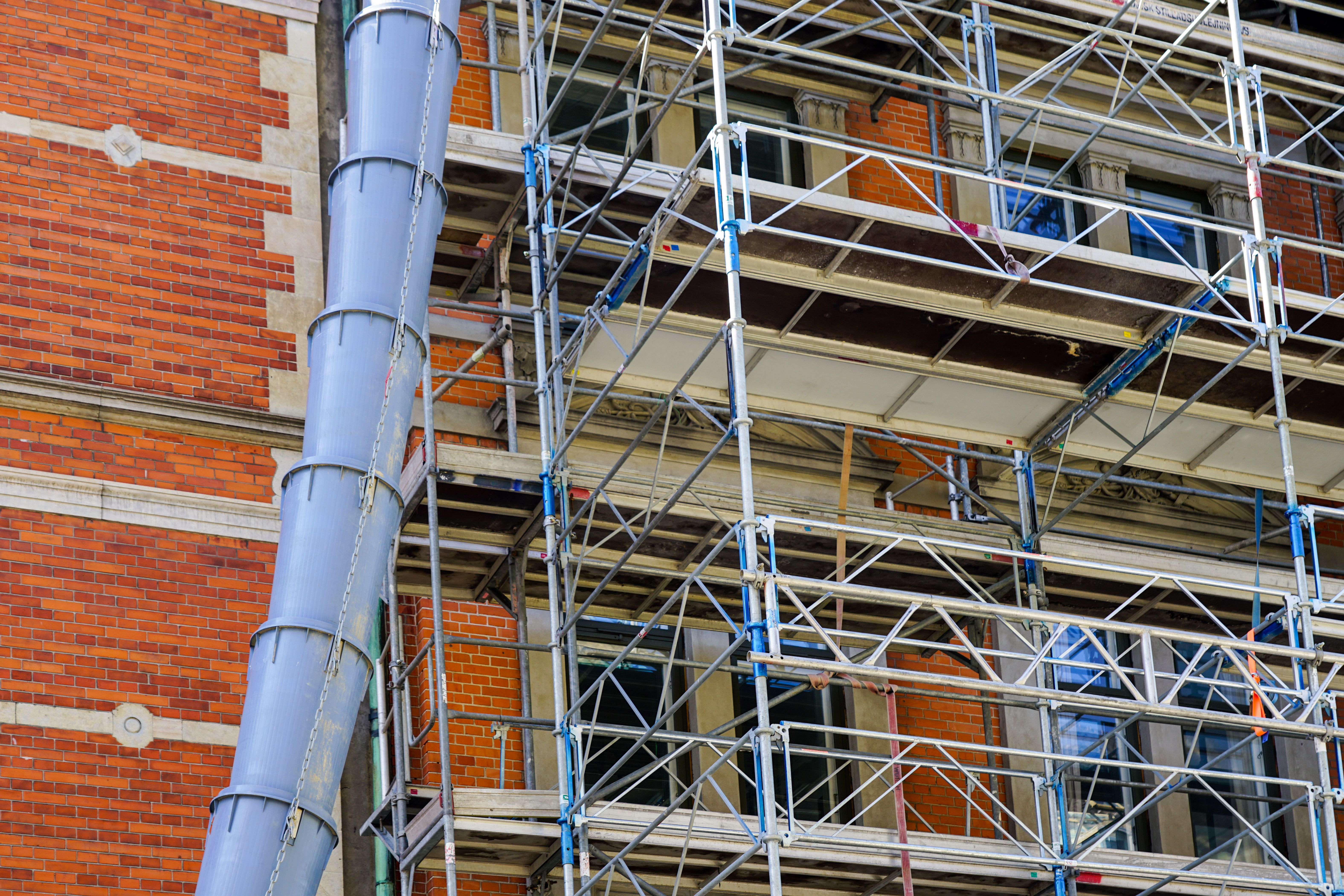 Blue plastic construction debris pipe and scaffolding at building renovation construction site