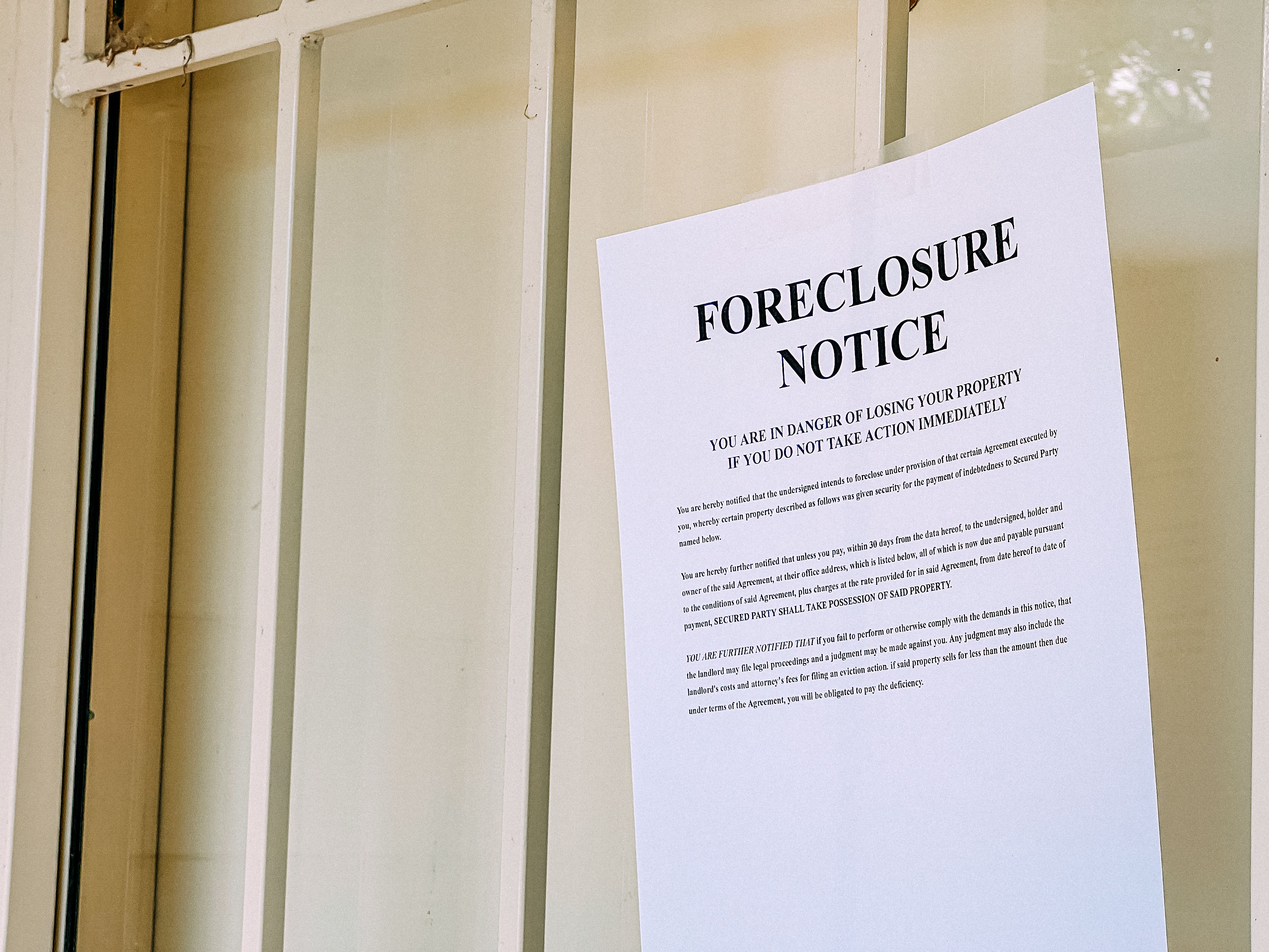 A Paper Foreclosure Notice on the Front Door of a Home in a USA Neighborhood with Copy Space A Paper Foreclosure Notice on the Front Door of a Home in a USA Neighborhood with Copy Space