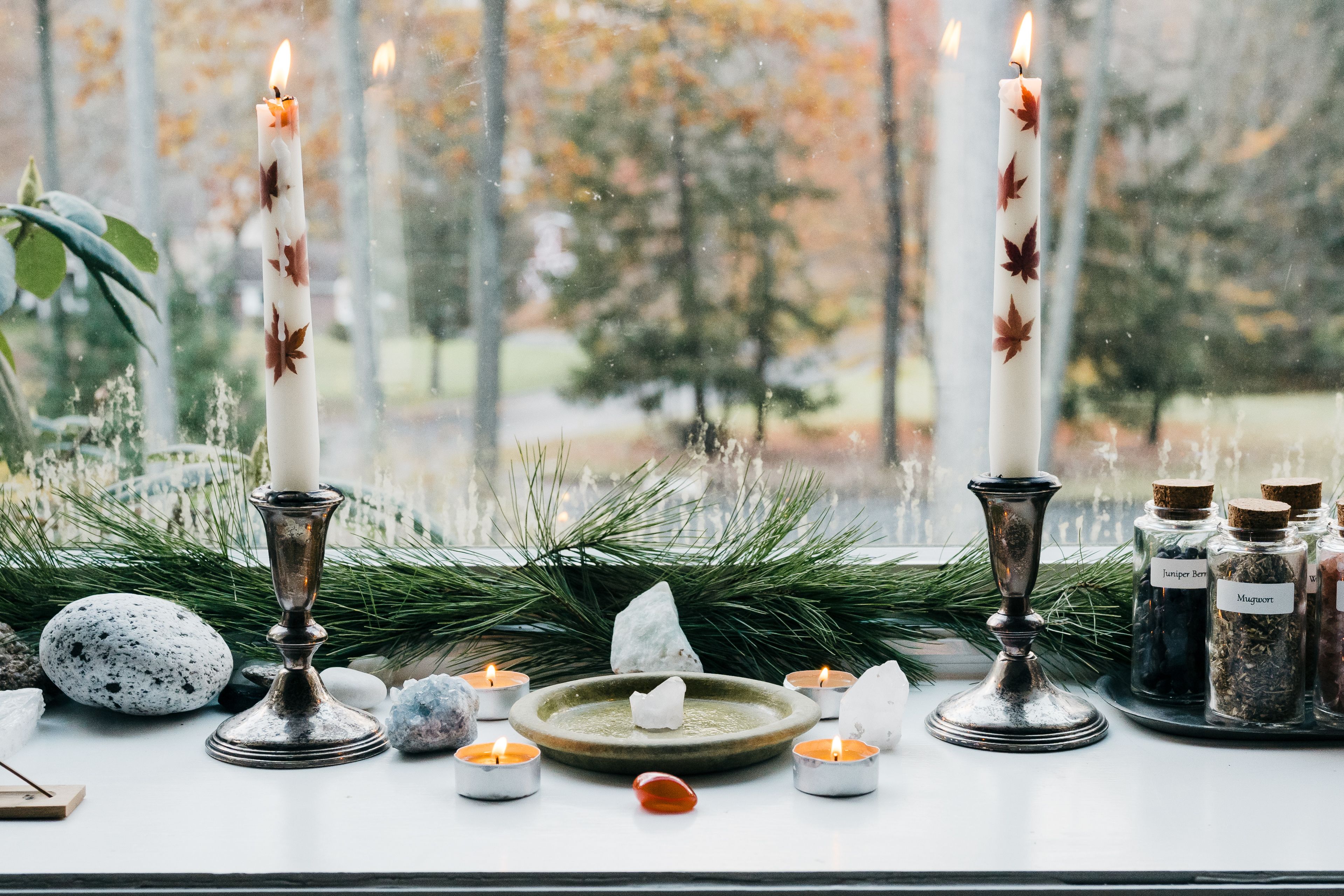 candles lit in a candle holder next to an outdoor window