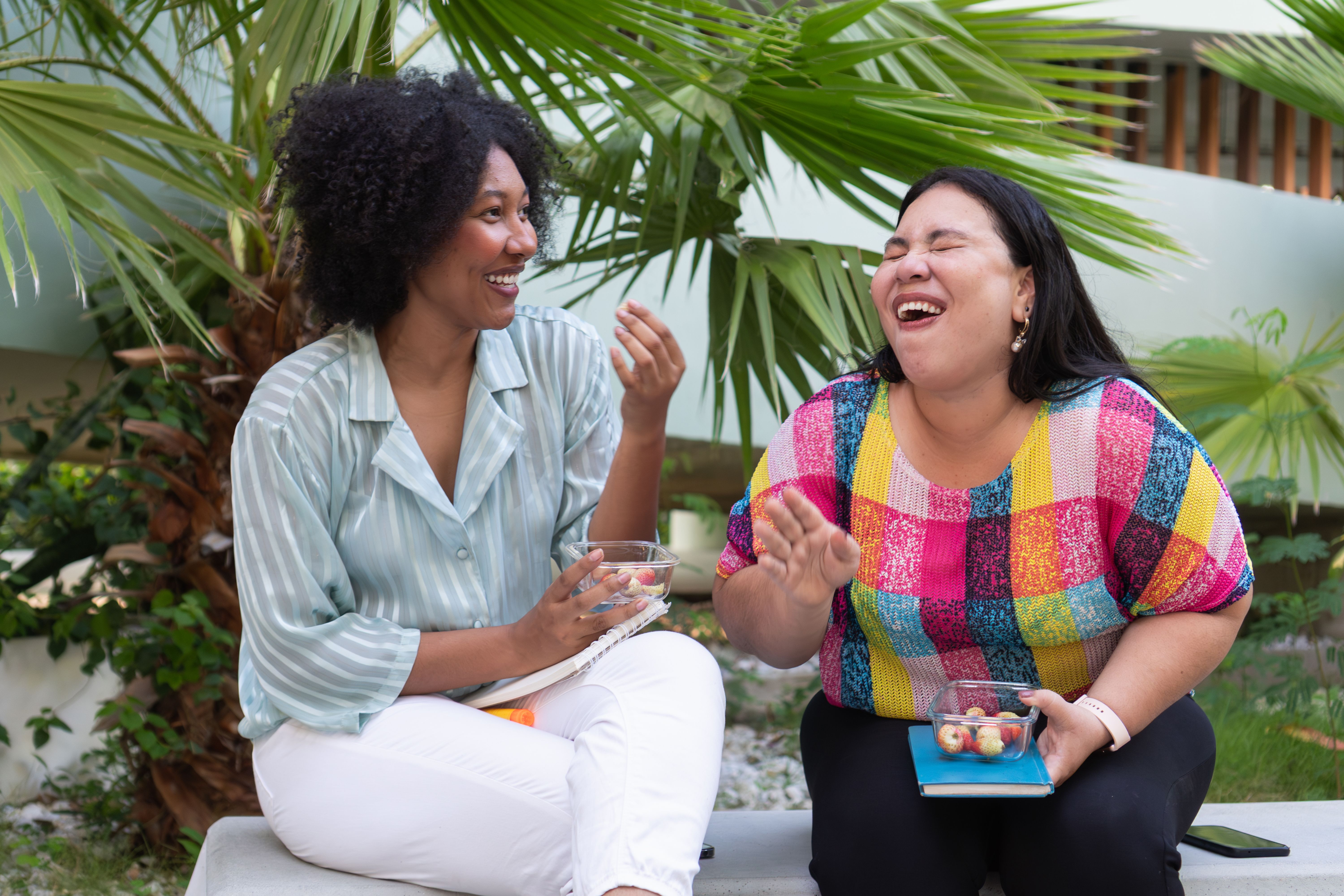 Two female colleagues enjoying lunch break together outdoors Two female colleagues enjoying lunch break together outdoors