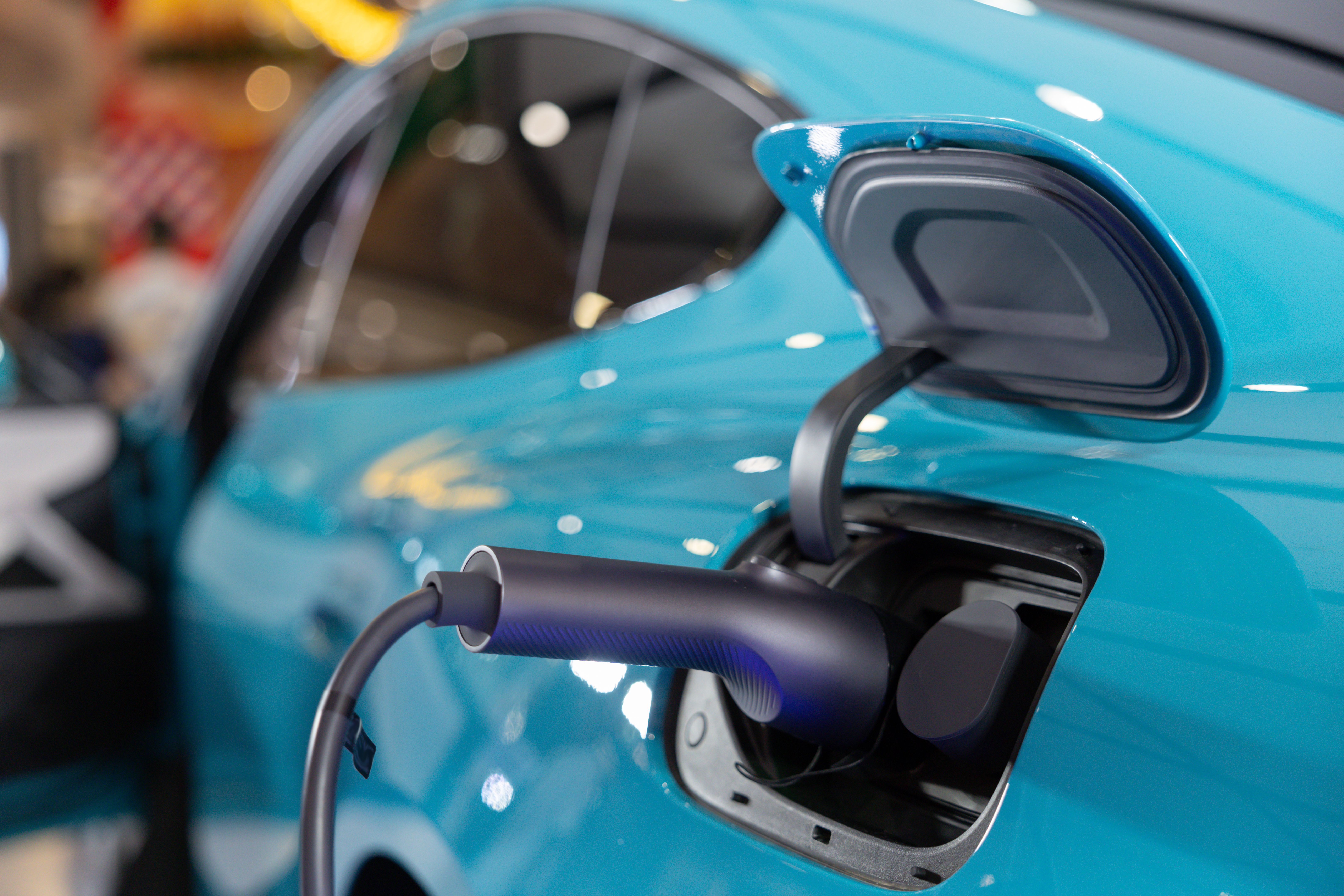 A EV car is being charged at a charging station A EV car is being charged at a charging station