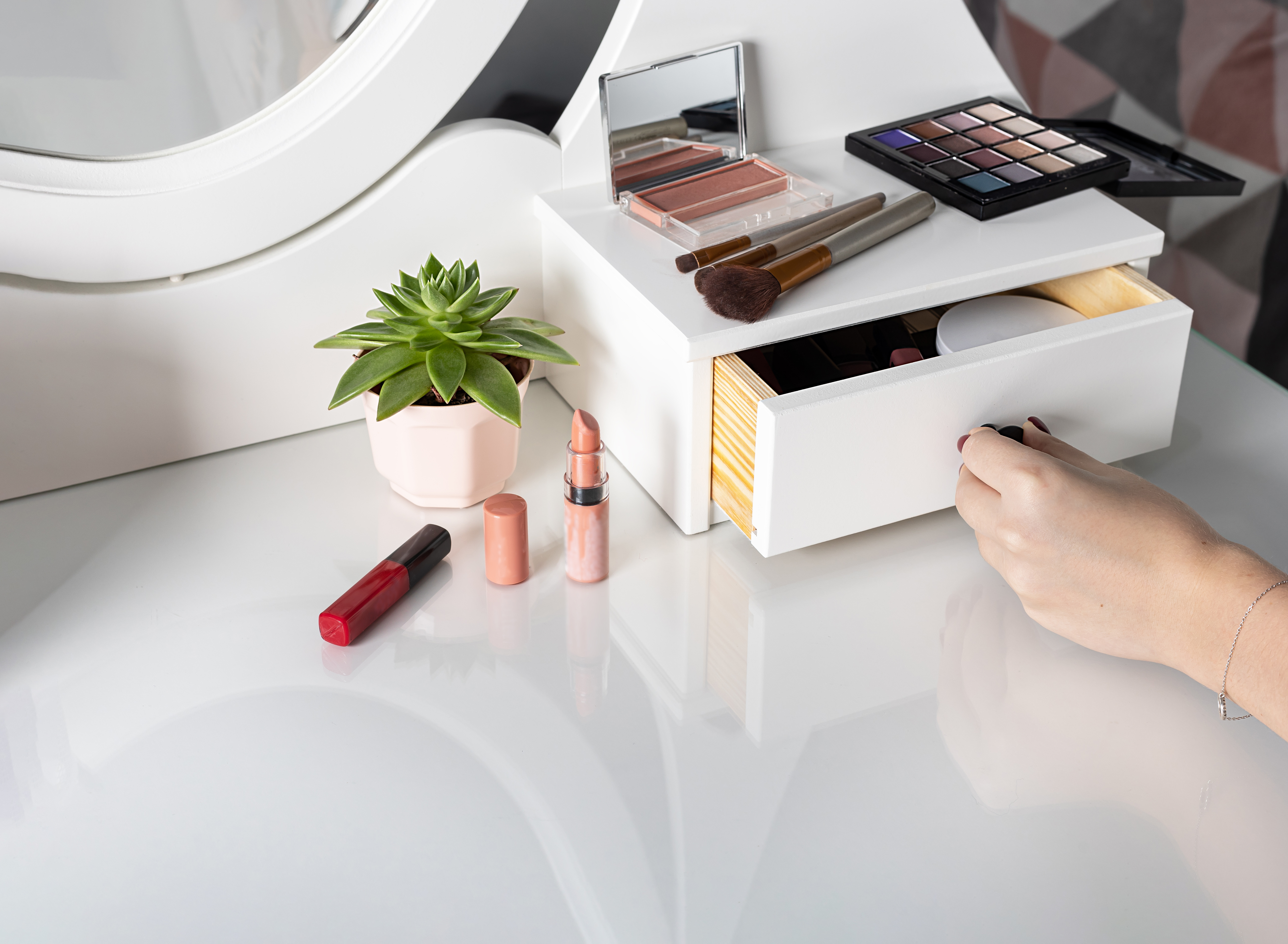 woman opens a drawer of white dressing table with products for make-up. Make-up accessories in the workplace