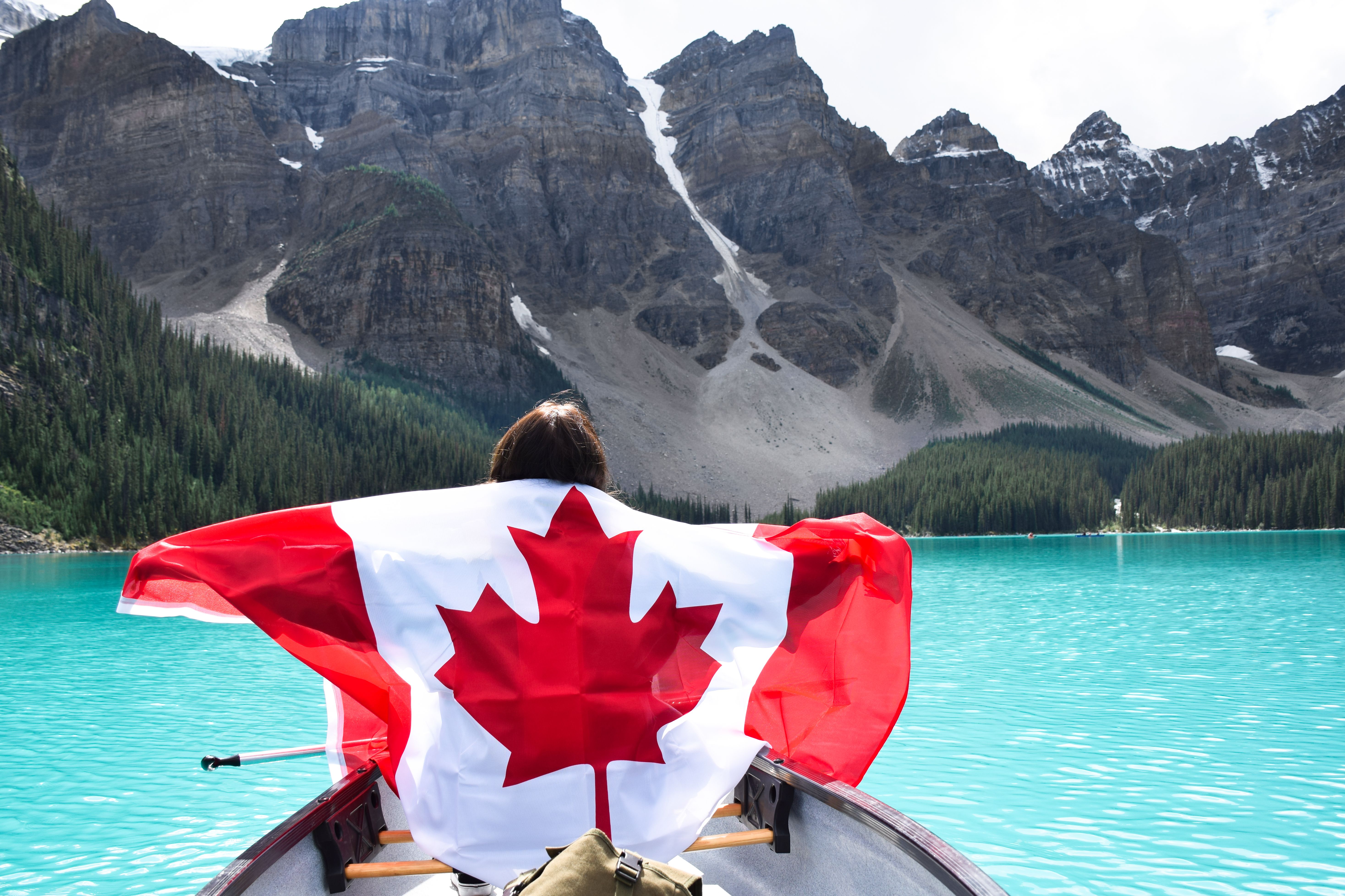 Young girl in a canoe holding canadian flag with spread out arms