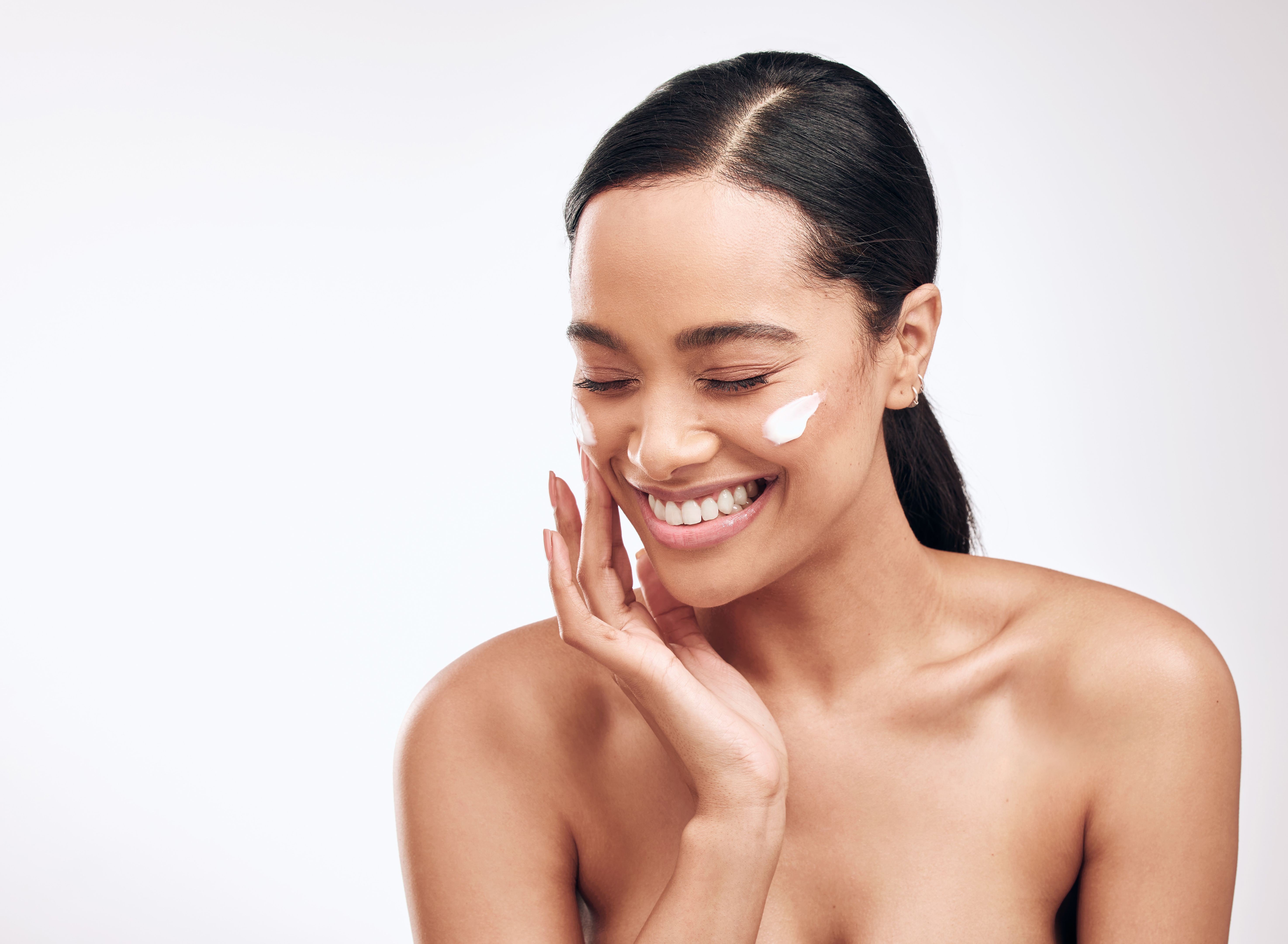 Studio shot of a beautiful young woman applying moisturiser to her face Studio shot of a beautiful young woman applying moisturiser to her face