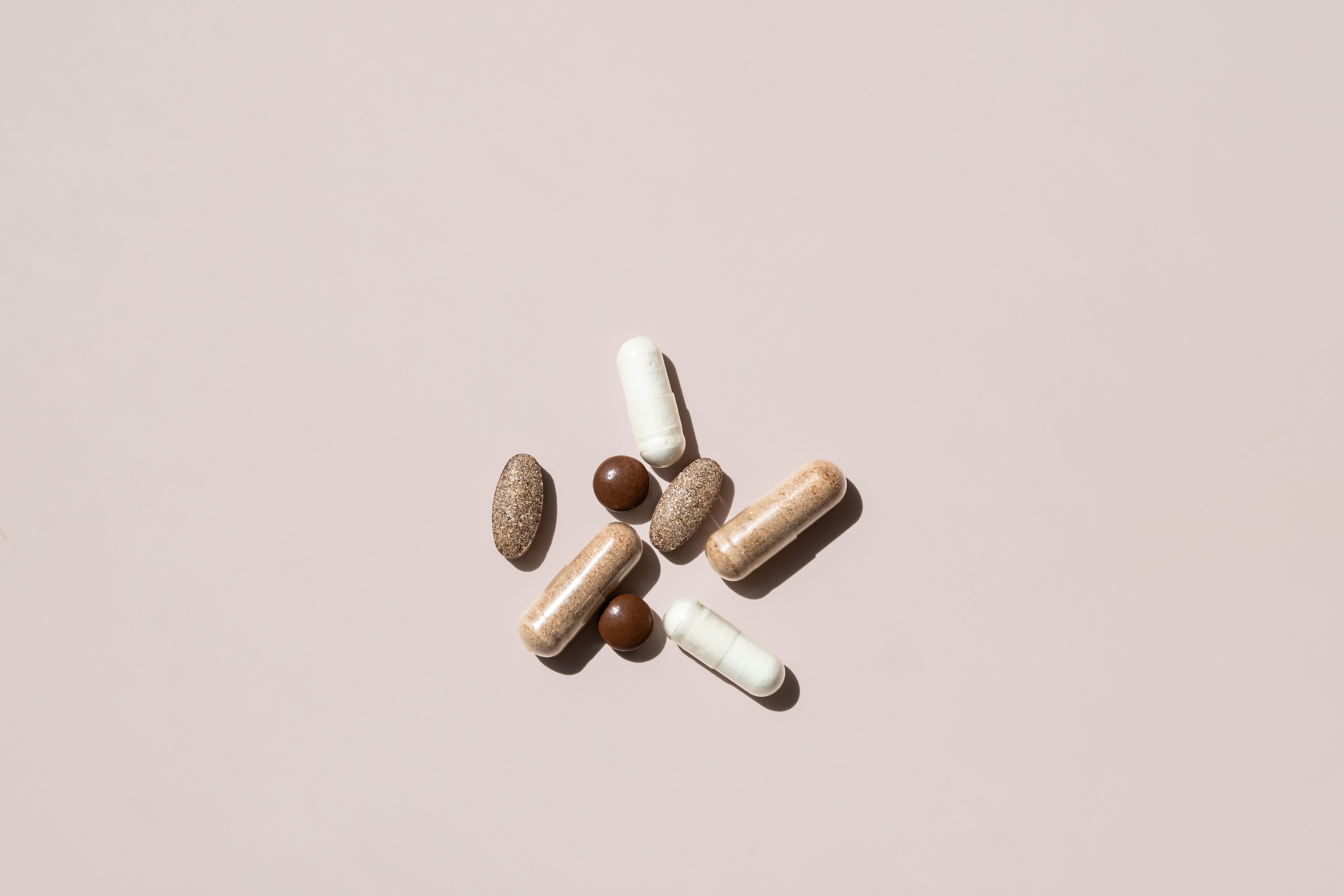 Collection of Various Dietary Supplements and Vitamins Arranged on Light Background. The Capsules are in Different Shapes and Colors.