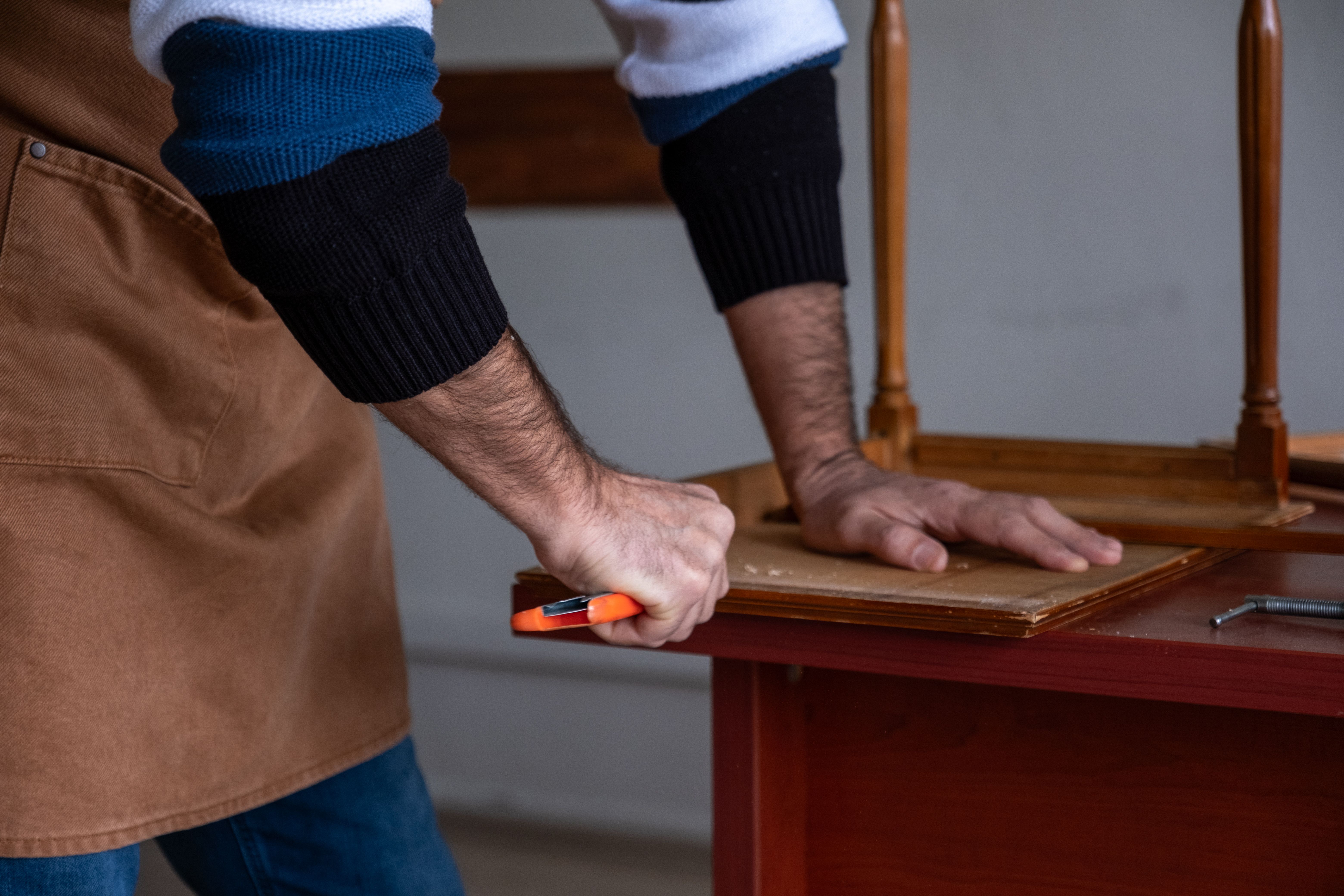 Carpenter restoring old furniture with chisel and hammer