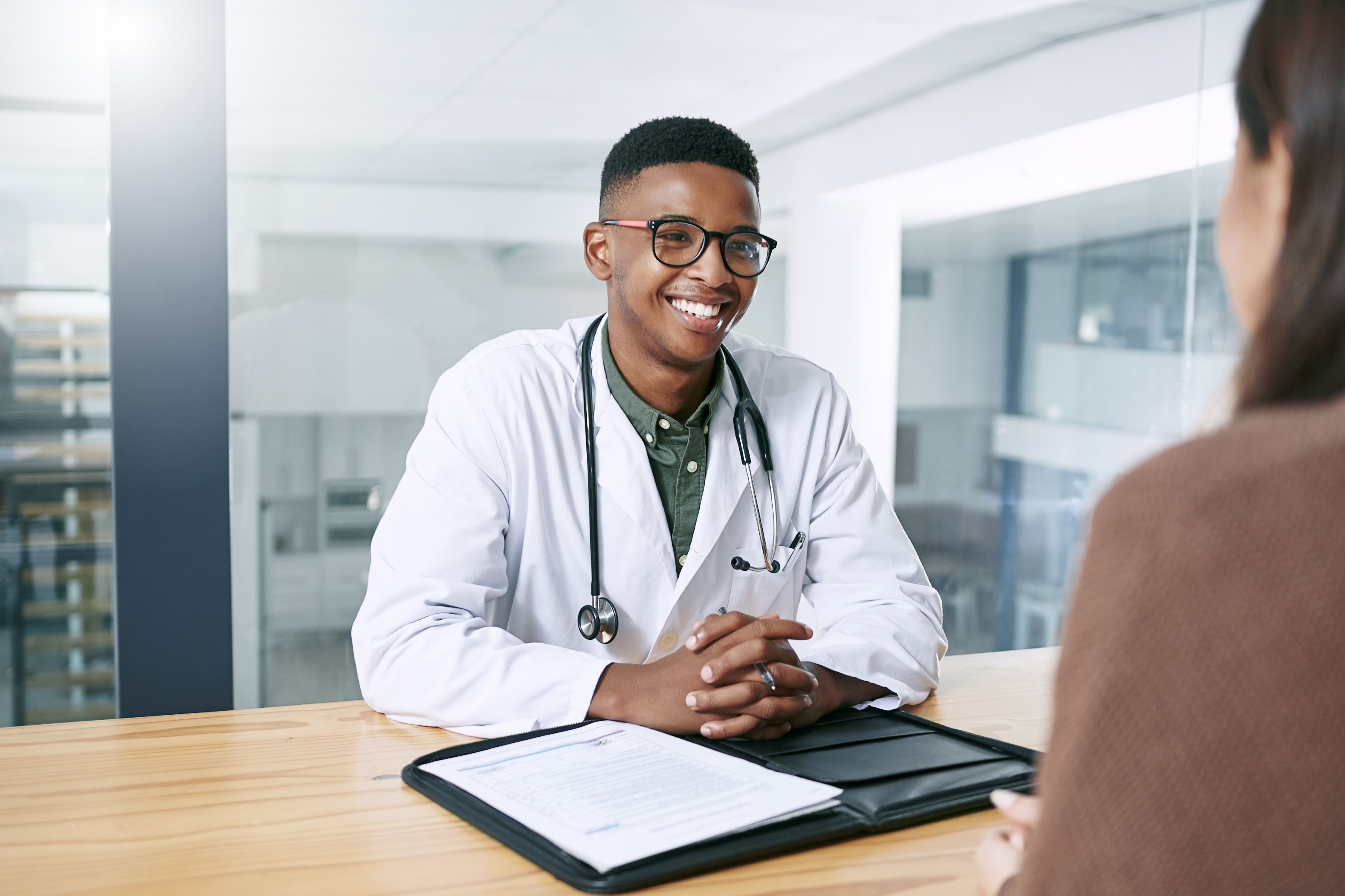 Shot of a handsome young doctor sitting with his patient during a consultation in the clinic