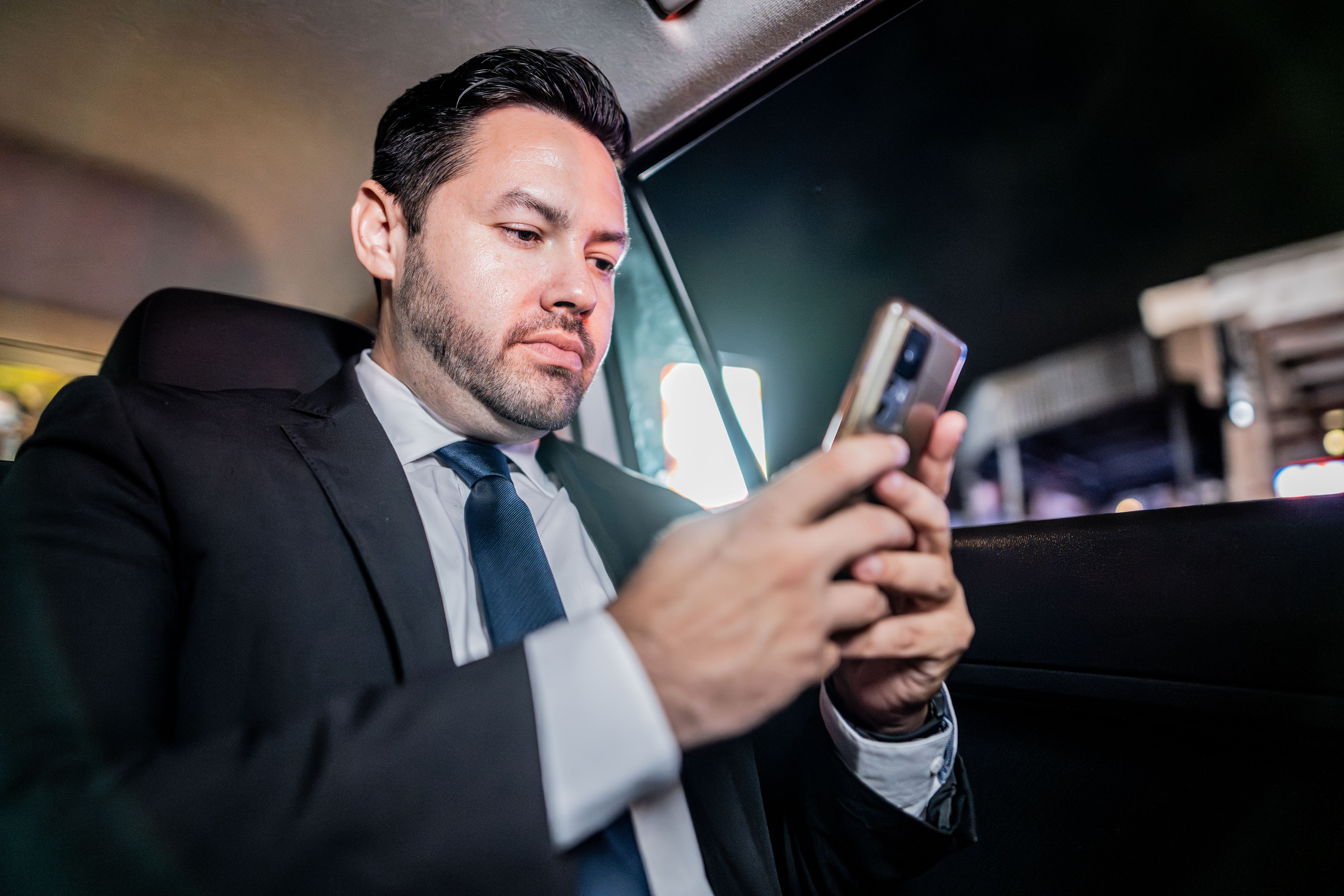 Mid adult businessman using mobile phone inside a taxi