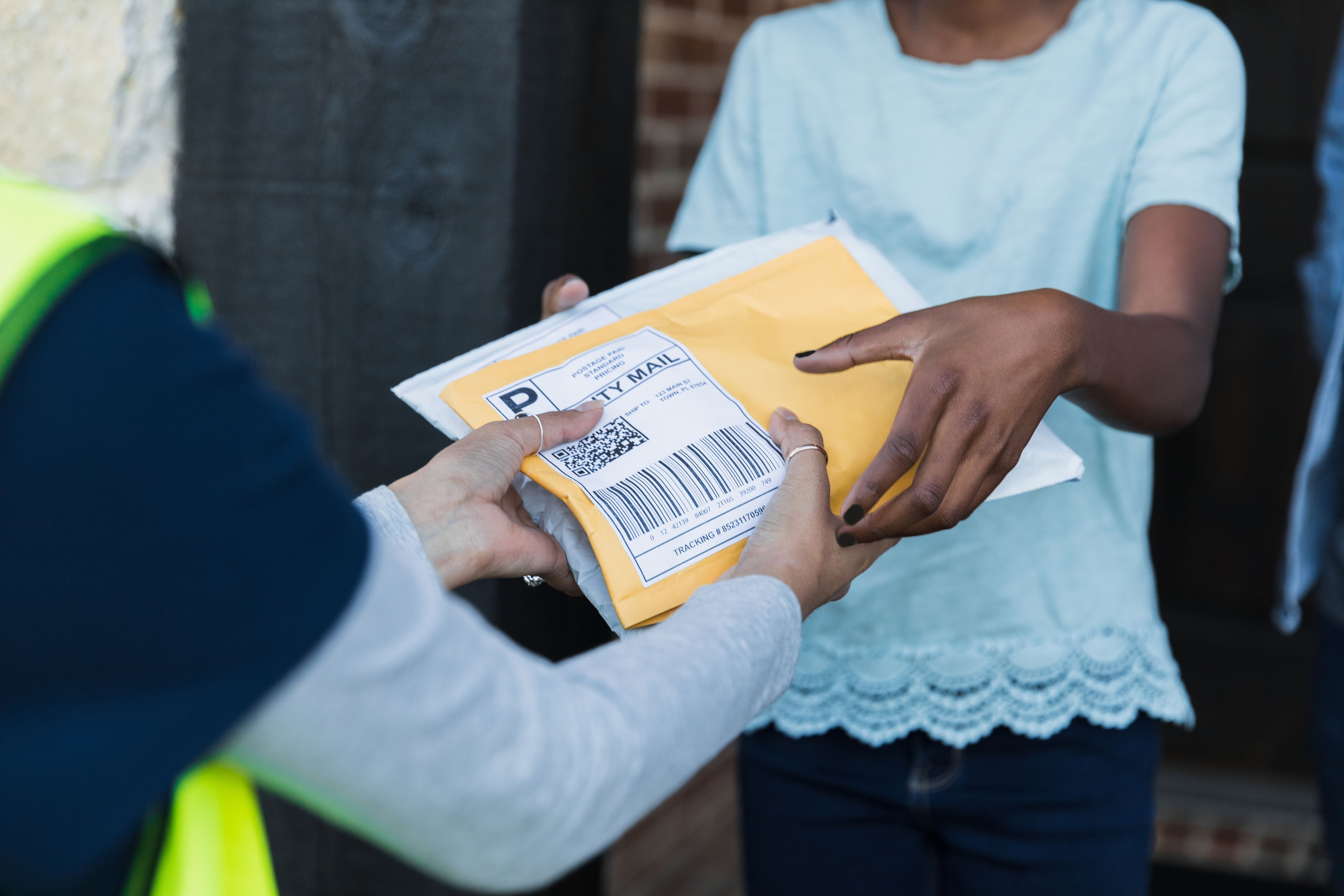 Focus on unrecognizable girl receiving packages from unrecognizable mail person