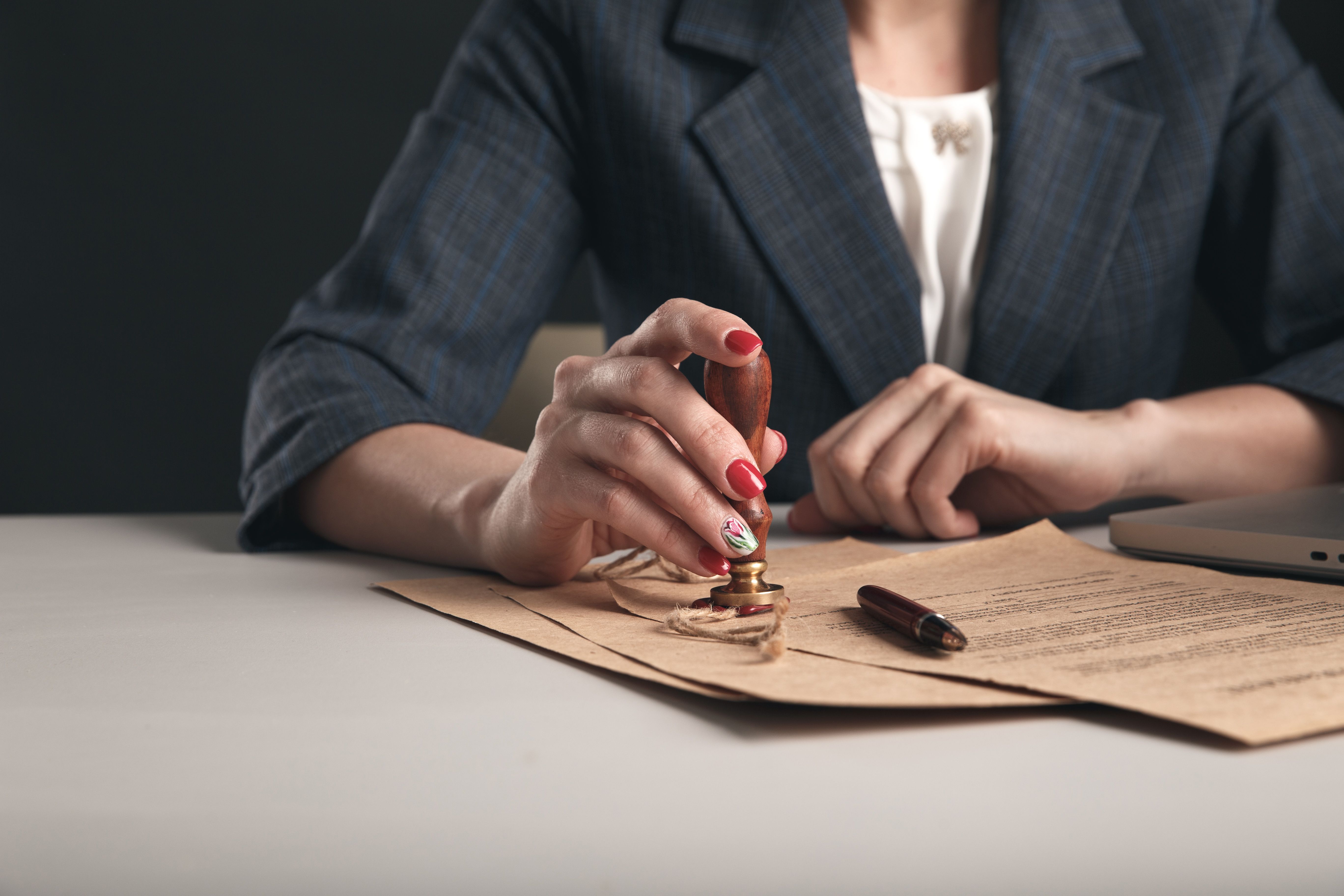 Woman notary with paper documents and pen sitting at the desk.