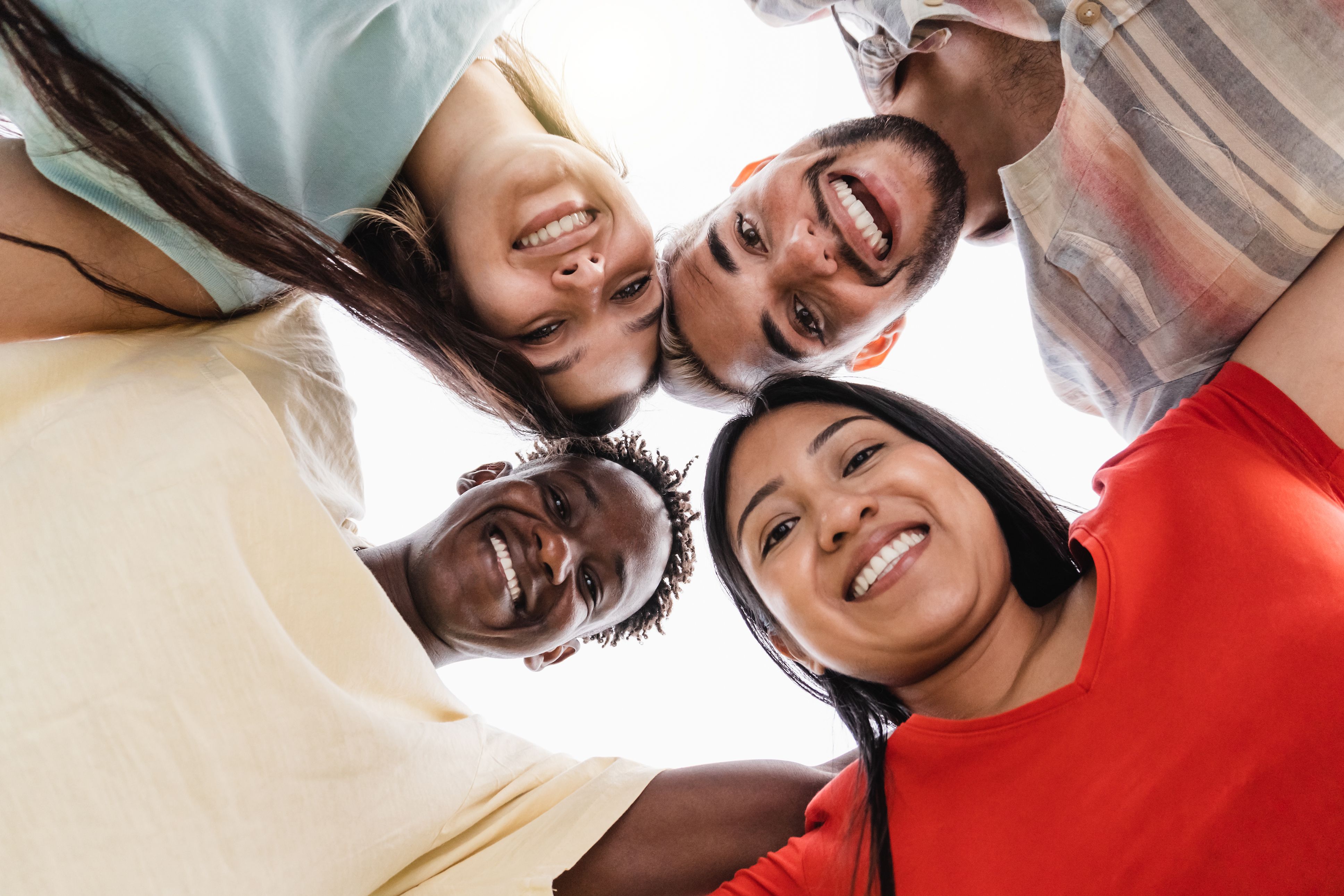 Group of diverse friends hugging in circle - Happy people having fun outdoor - Main focus in gay man face