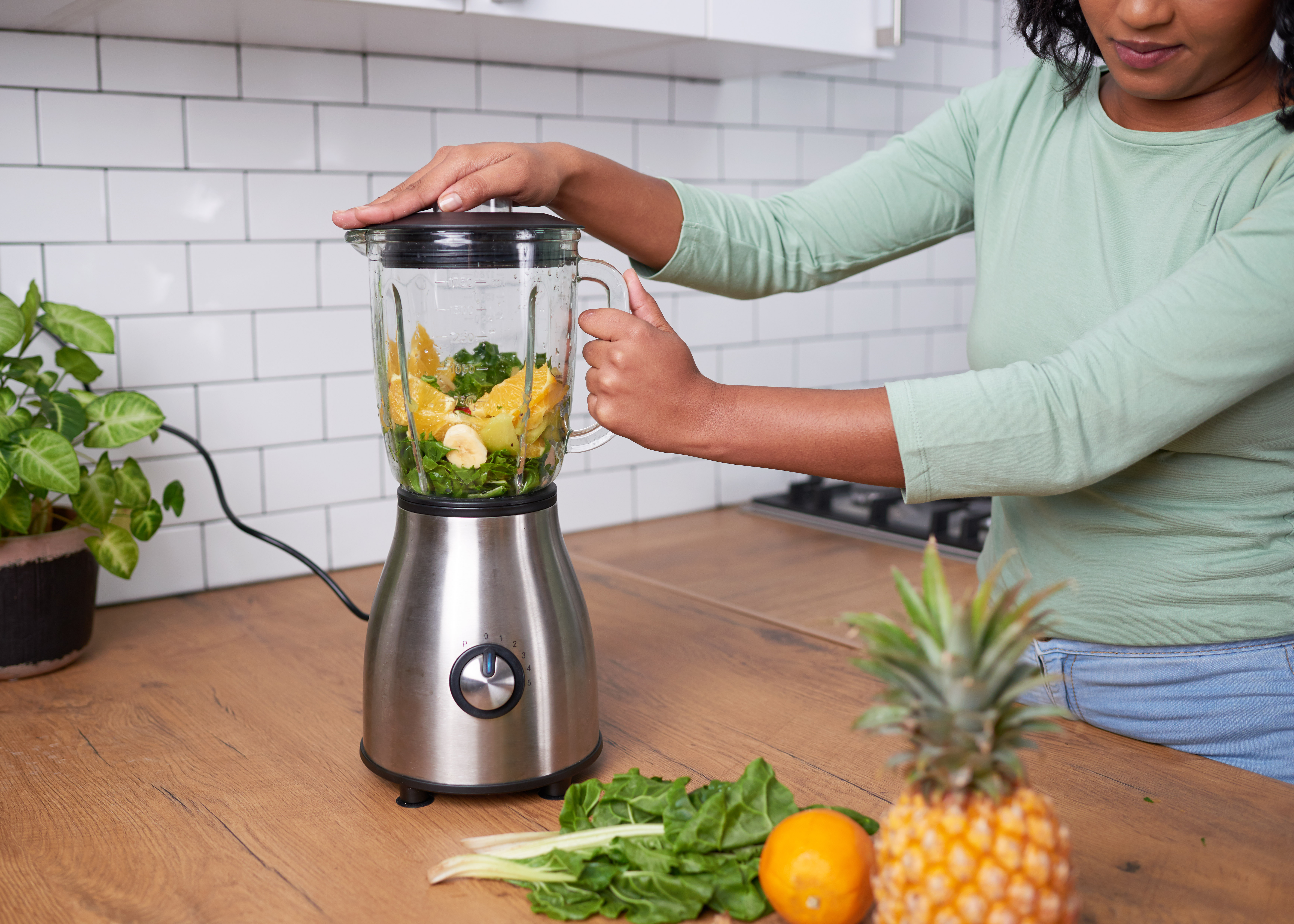 A young multi-ethnic woman blends a smoothie on kitchen counter