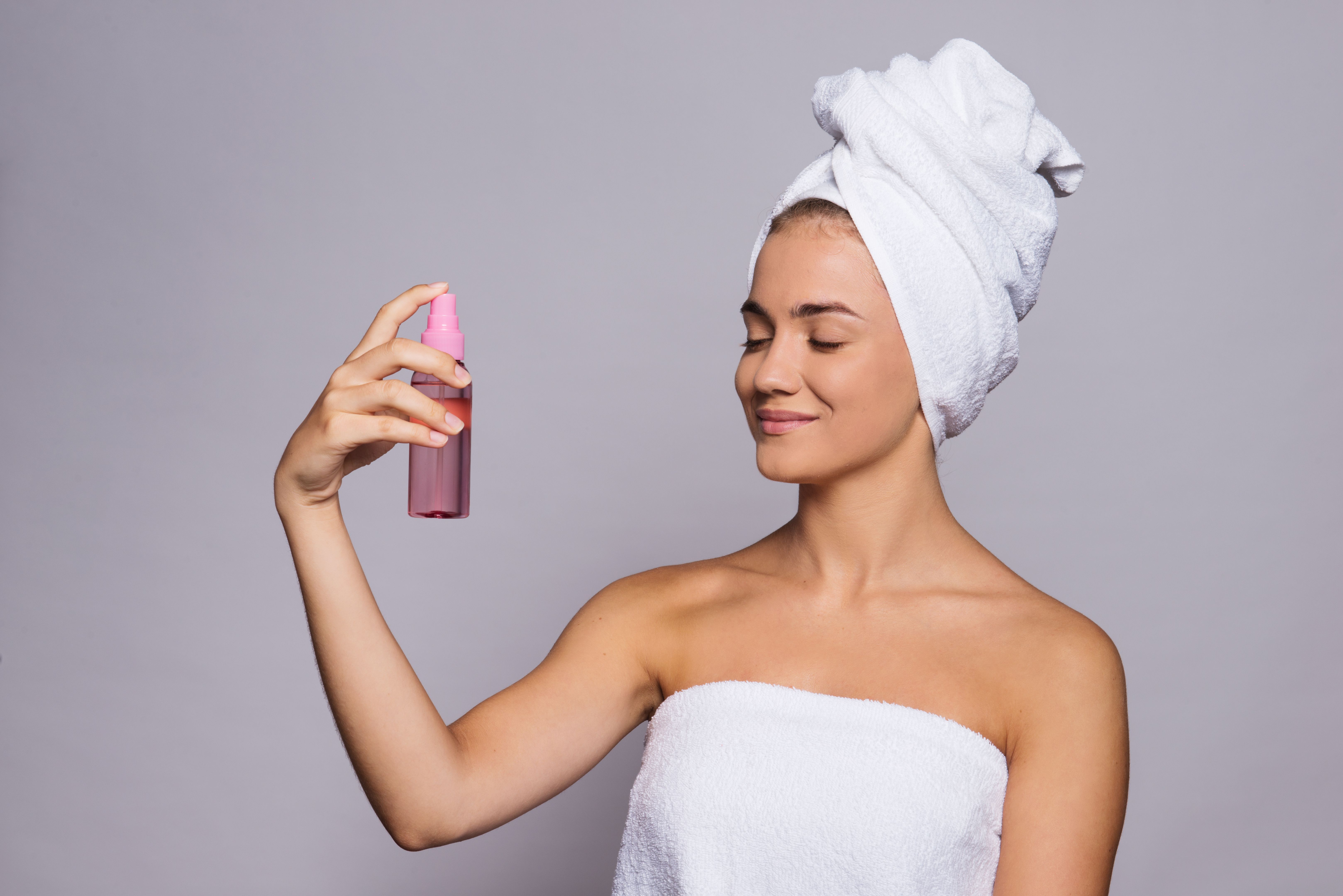 A portrait of young woman with spray in a studio, beauty and skin care. A portrait of young woman with spray in a studio, beauty and skin care.