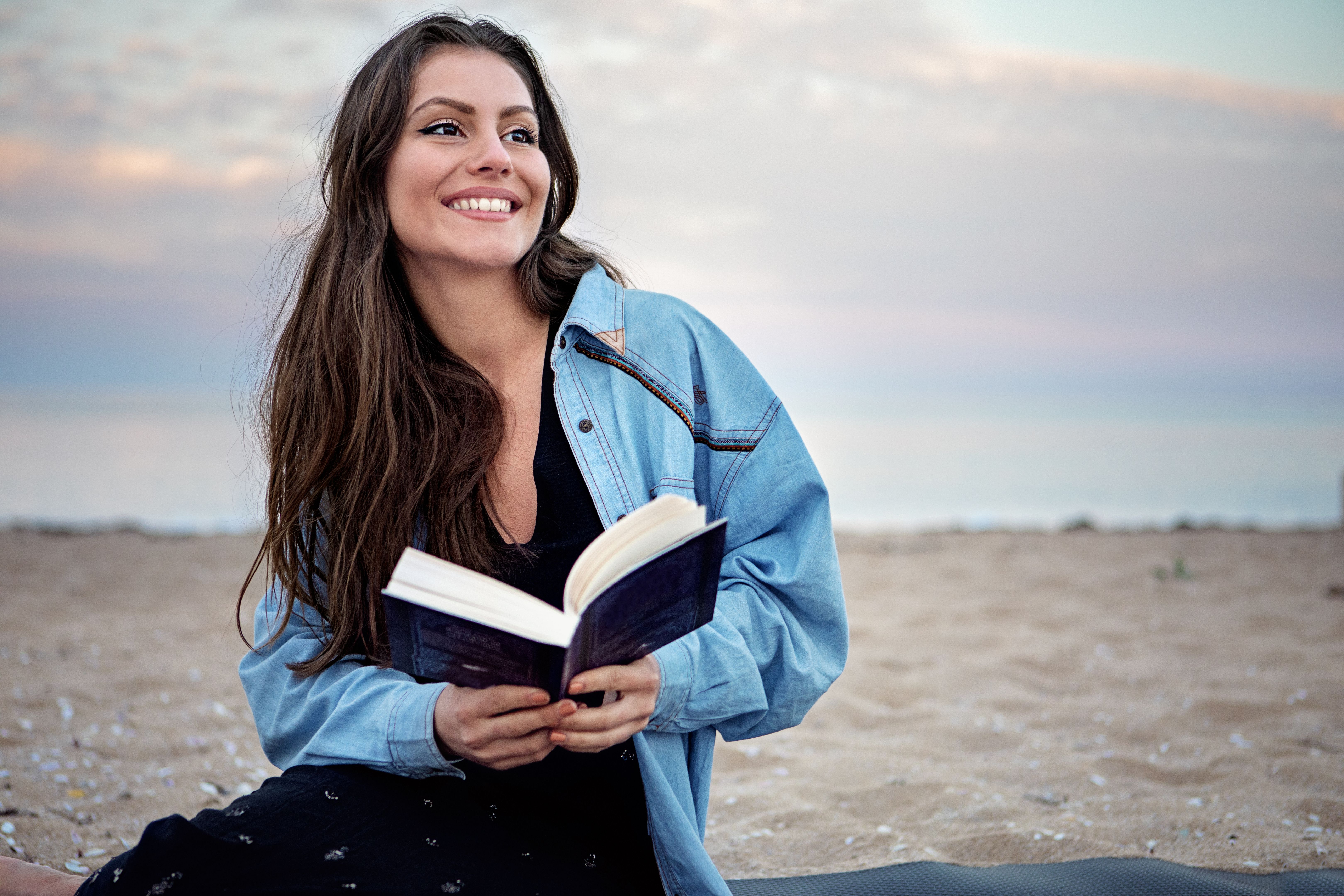 Portrait of young woman reading book on the beach