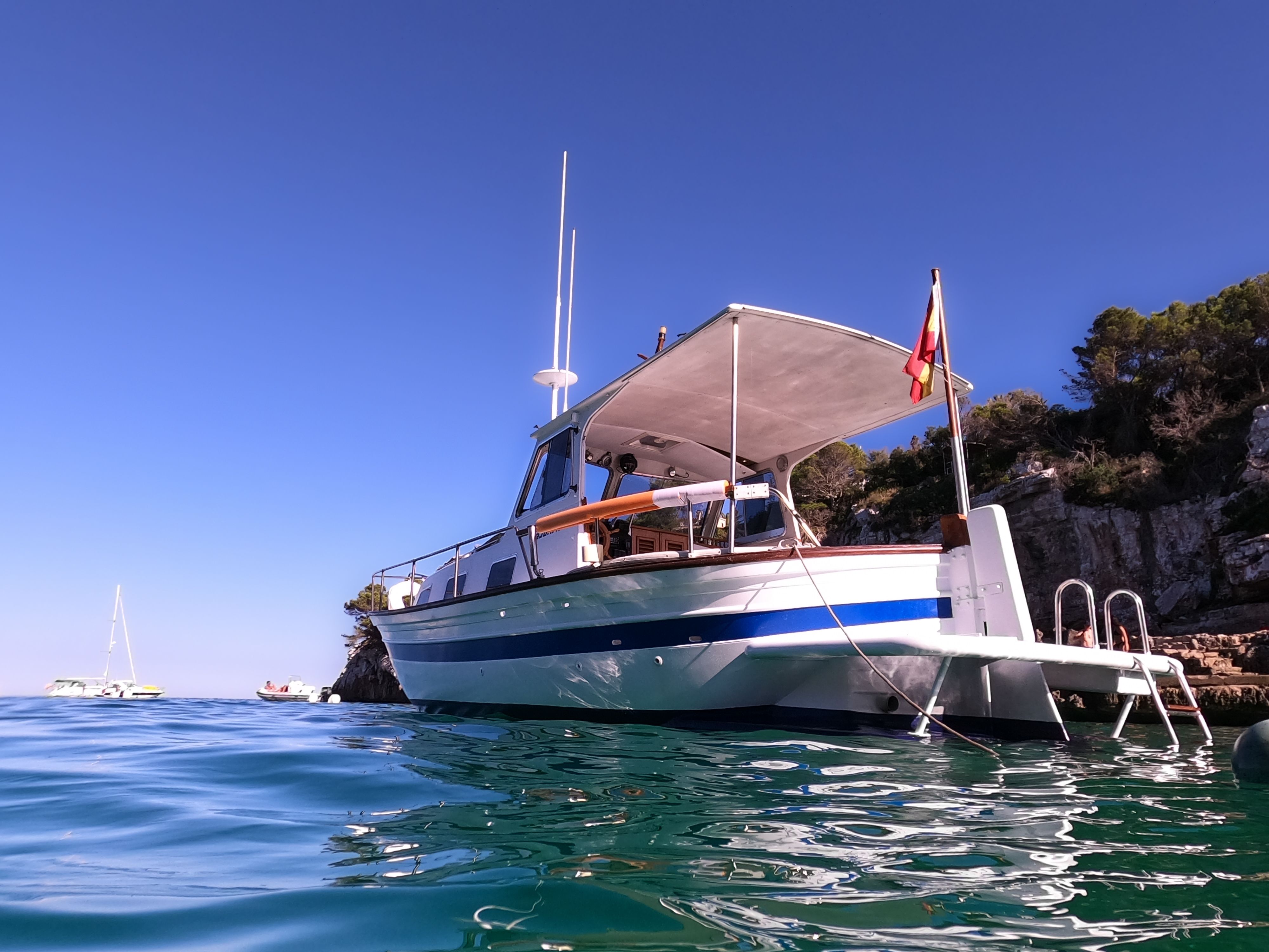 Vista de bajo ángulo desde el agua de un barco aislado sin gente anclada en una cala en Mallorca